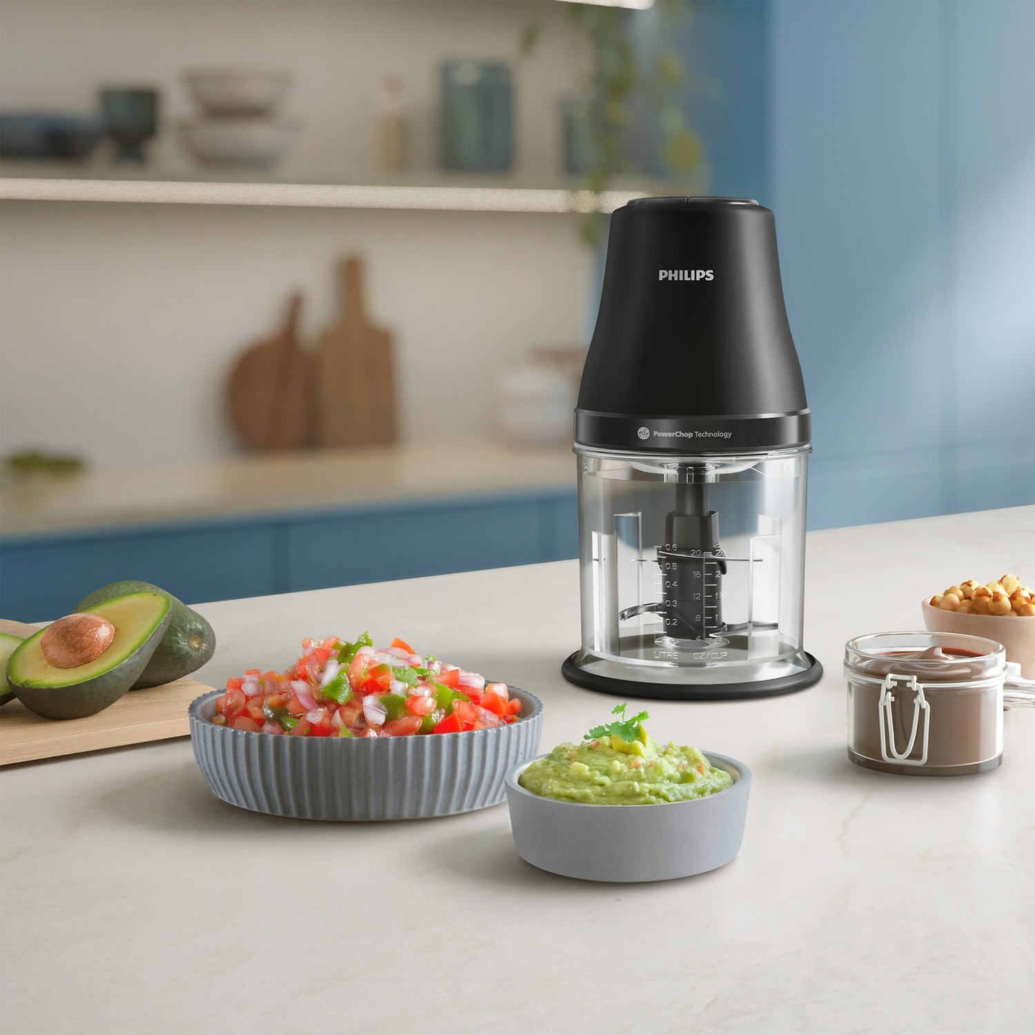 A black Philips food processor with ingredients like avocado, salsa, and guacamole on a white countertop.