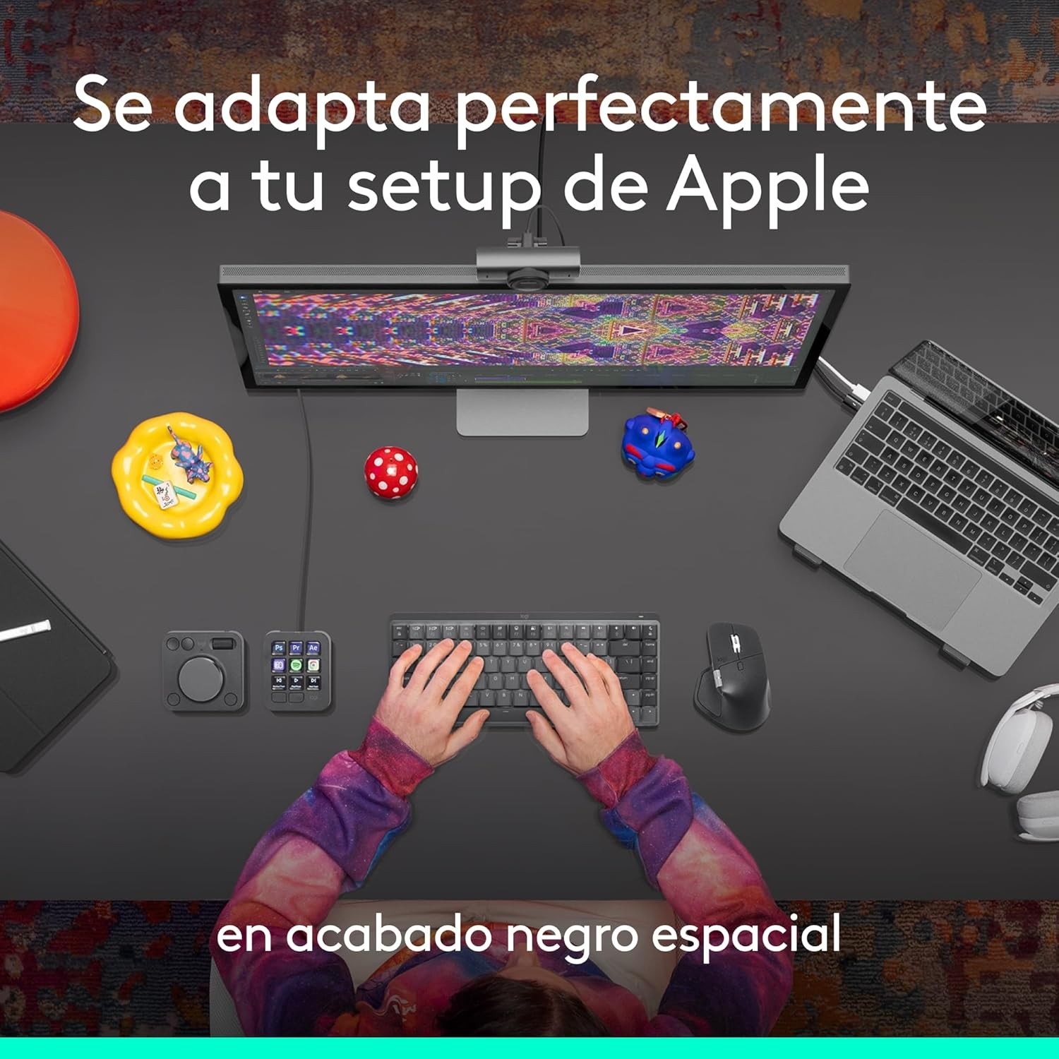 Vista superior de un espacio de trabajo con monitor, portátil, teclado, ratón y accesorios. Manos en el teclado. Texto: Se adapta...
