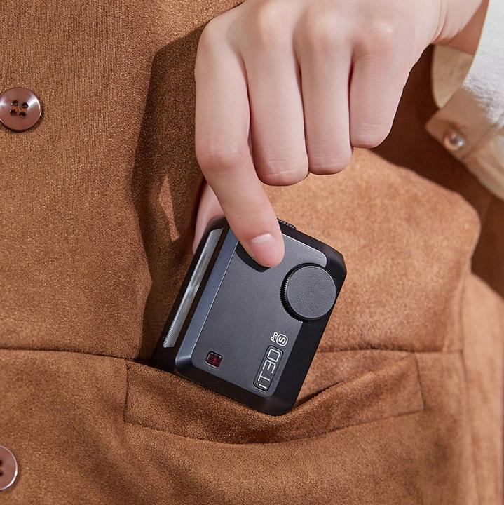 Eine Hand, die ein schwarzes IT30s-Gerät in die Tasche einer braunen Jacke steckt. Das Gerät hat einen Knopf und ein rotes Licht.