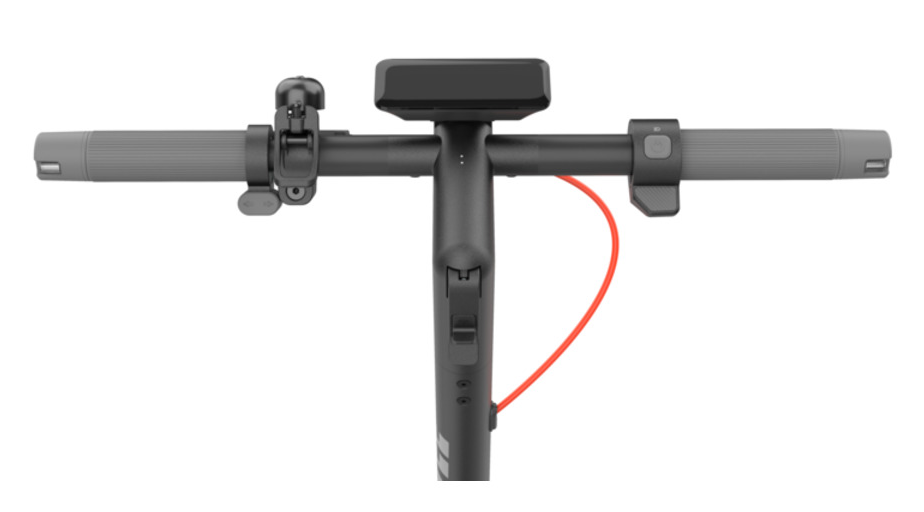 Zbliżenie kierownicy skutera. Ma szare uchwyty, czarny wyświetlacz i czerwony kabel. Widoczne są przyciski i dźwignie.