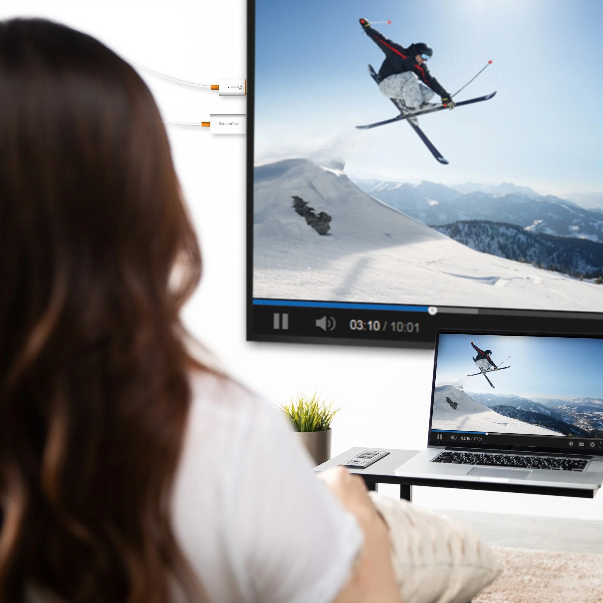 Egy nő síelőről szóló videót néz a TV-n és a laptopon. Kábelek csatlakoznak a TV-hez.
