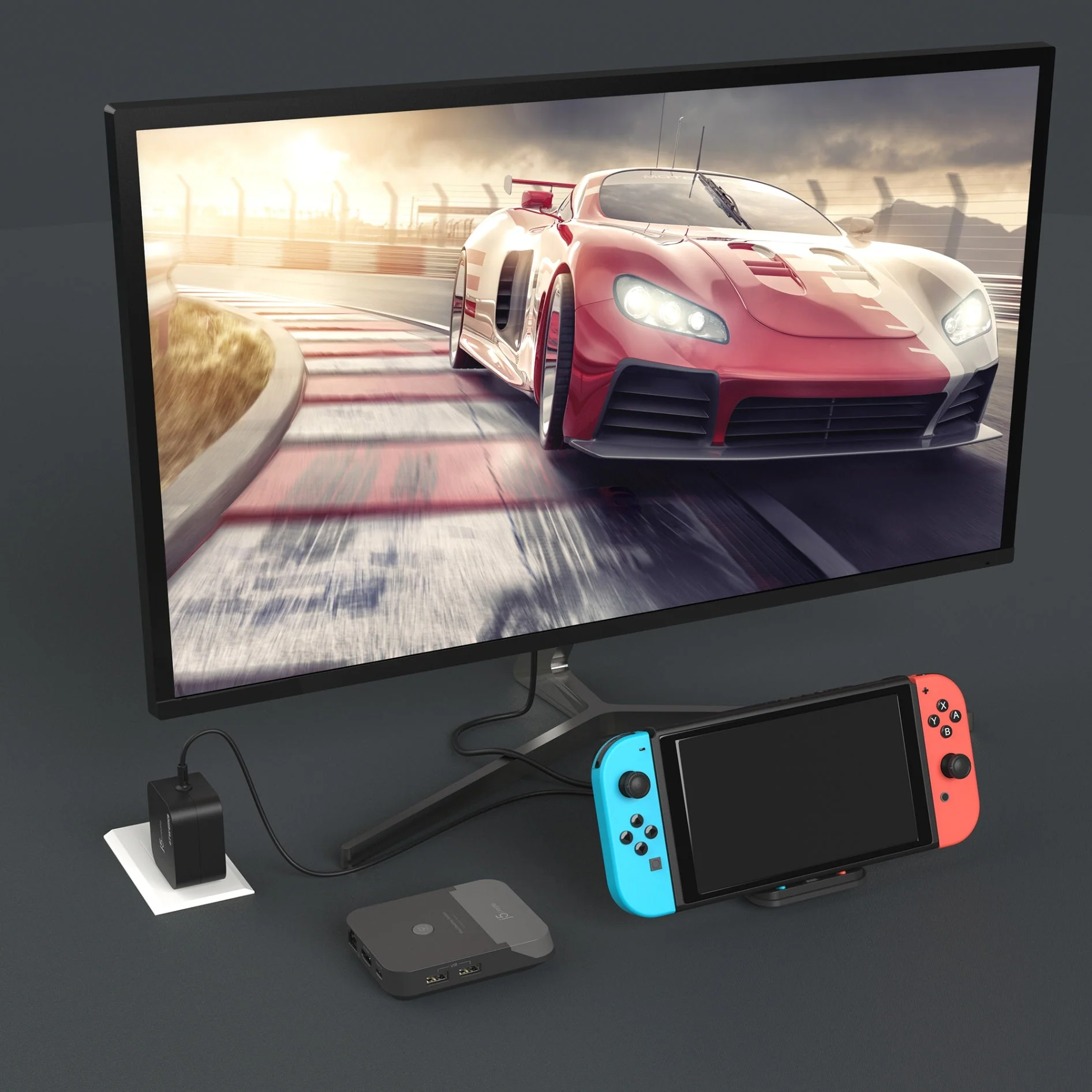 Versenyautó a monitoron, Nintendo Switch-csel, dokkolóval és kiegészítőkkel sötét felületen.