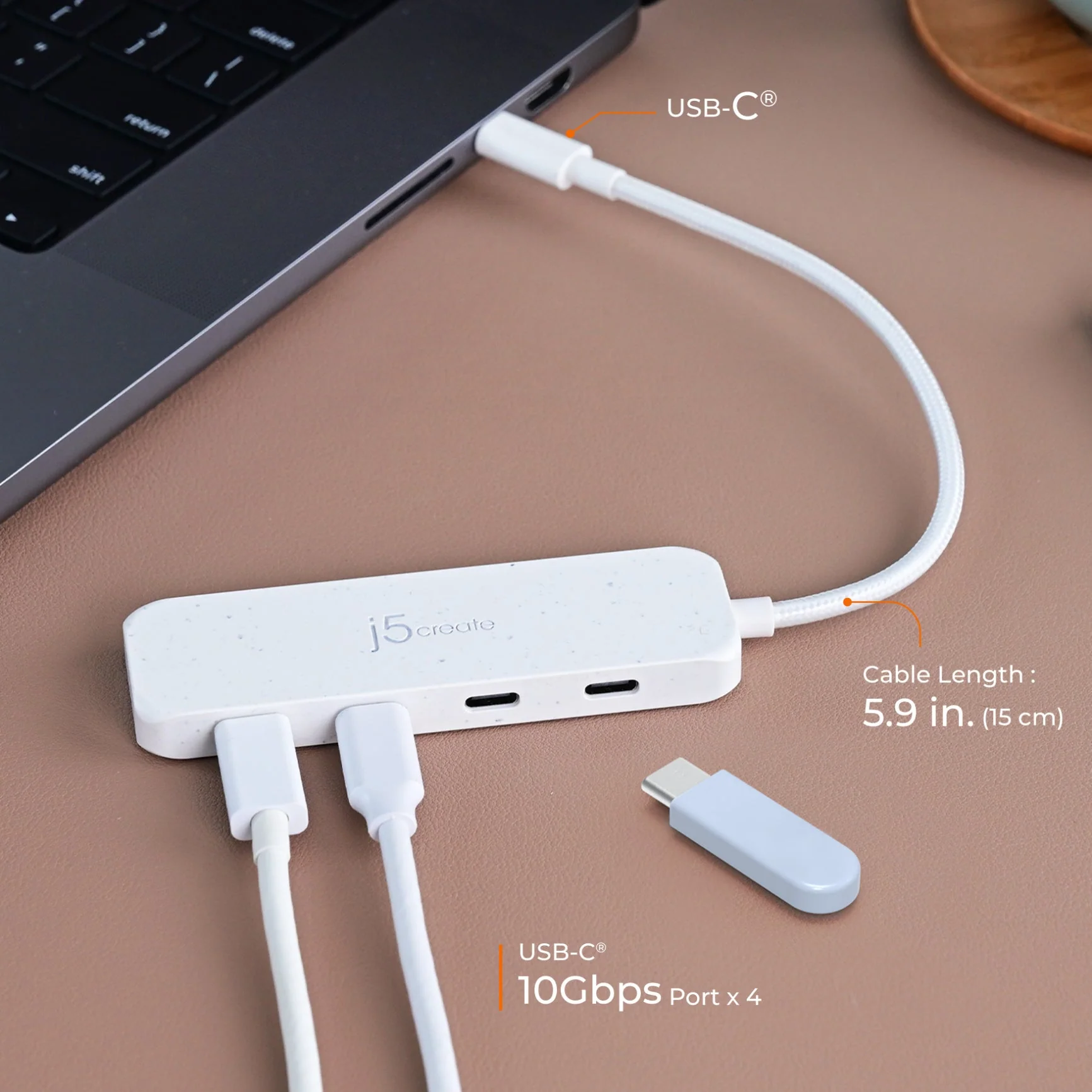 Egy fehér USB-C hub laptophoz csatlakoztatva. Portokkal, kábelekkel és egy külön USB-C adapterrel rendelkezik.