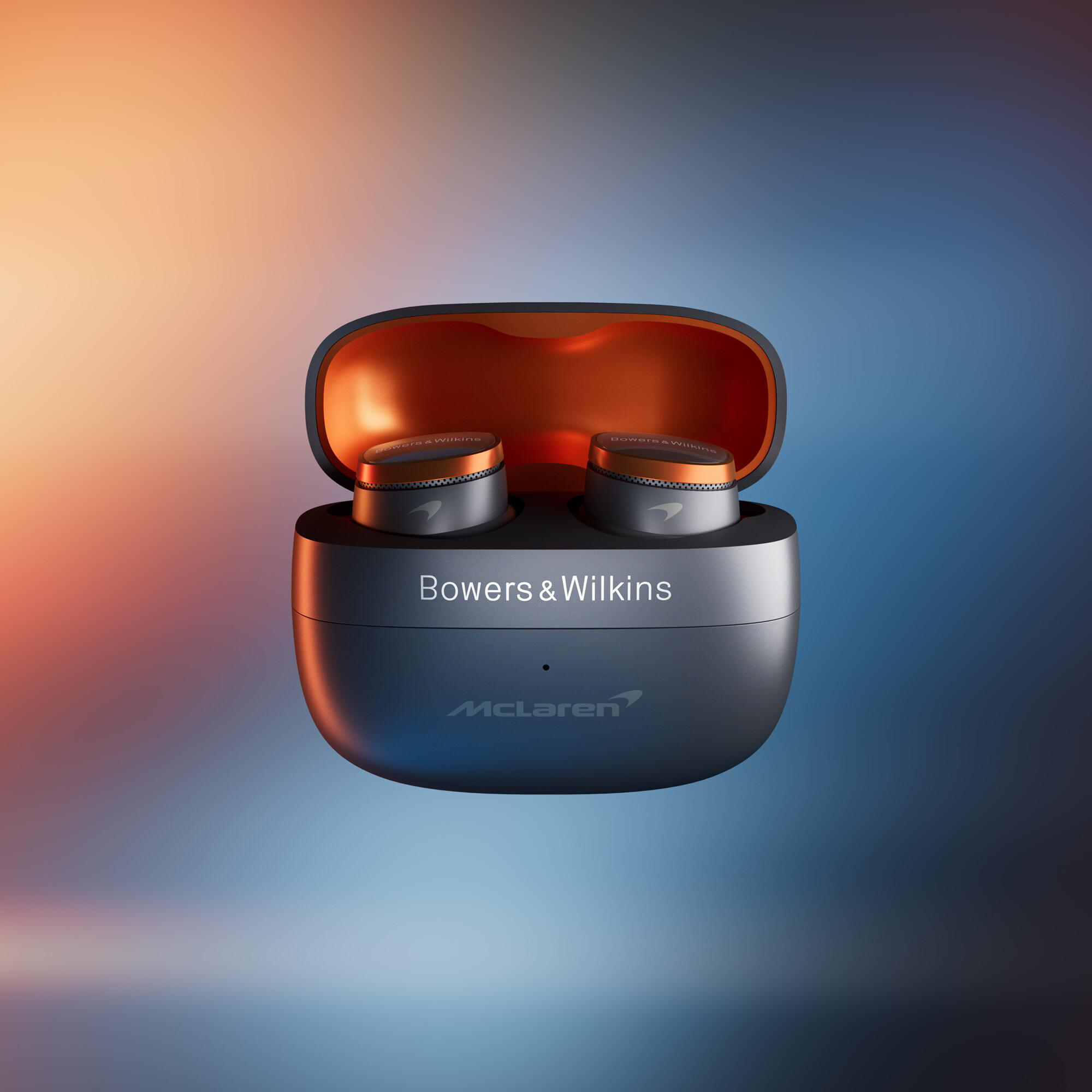 Ohrhörer in einem offenen Etui mit dem Markennamen Bowers & Wilkins und McLaren. Orange-Grau-Farbschema.