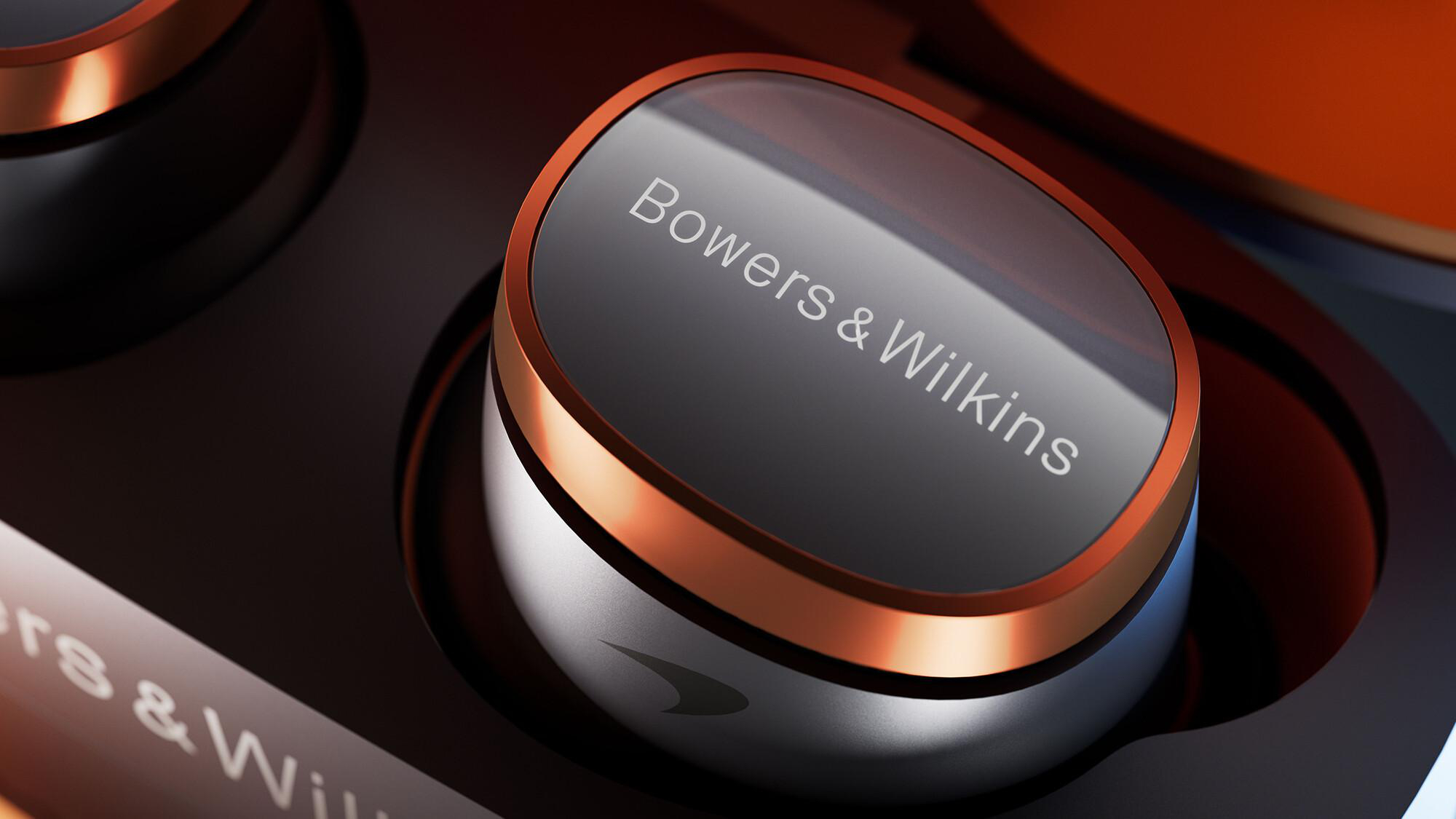 Nahaufnahme eines schwarzen und kupferfarbenen kabellosen Ohrhörers mit der Aufschrift 'Bowers & Wilkins'. Der Hintergrund ist verschwommen.