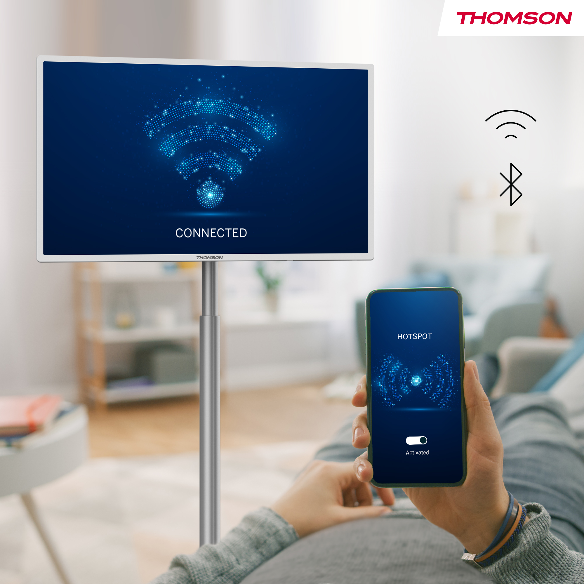 Un televisor muestra un icono de WiFi conectado. Un teléfono muestra el punto de acceso activado. Una persona sostiene el teléfono.