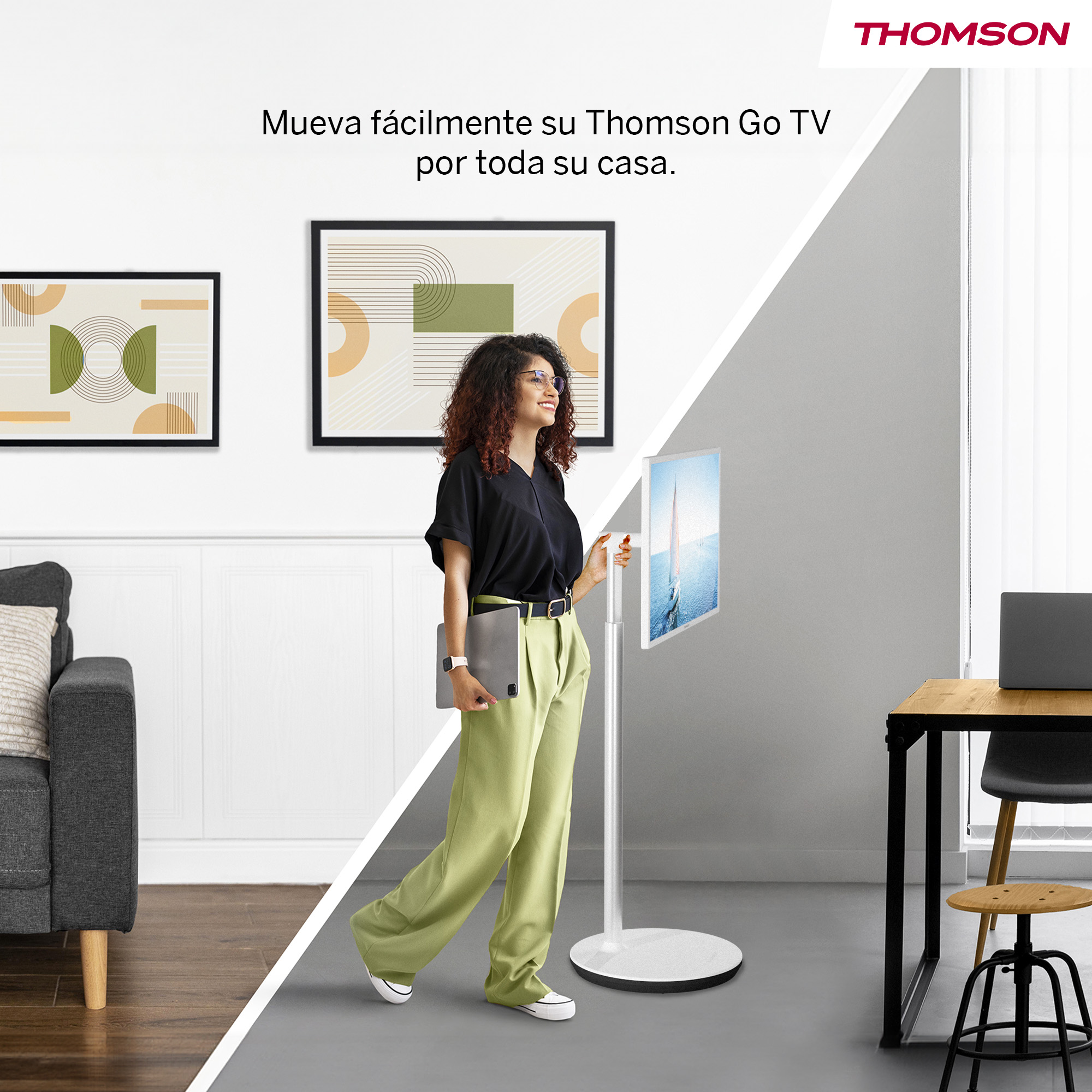 Mujer con portátil cerca del soporte de TV. Pinturas en la pared, sofá, mesa y silla al fondo. Logo Thomson arriba a la derecha.