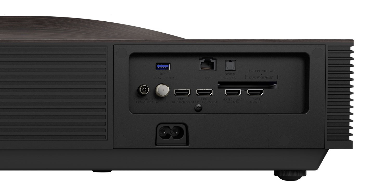 Tył czarnego projektora z różnymi portami, w tym HDMI, USB i LAN. Ma drewniany blat.