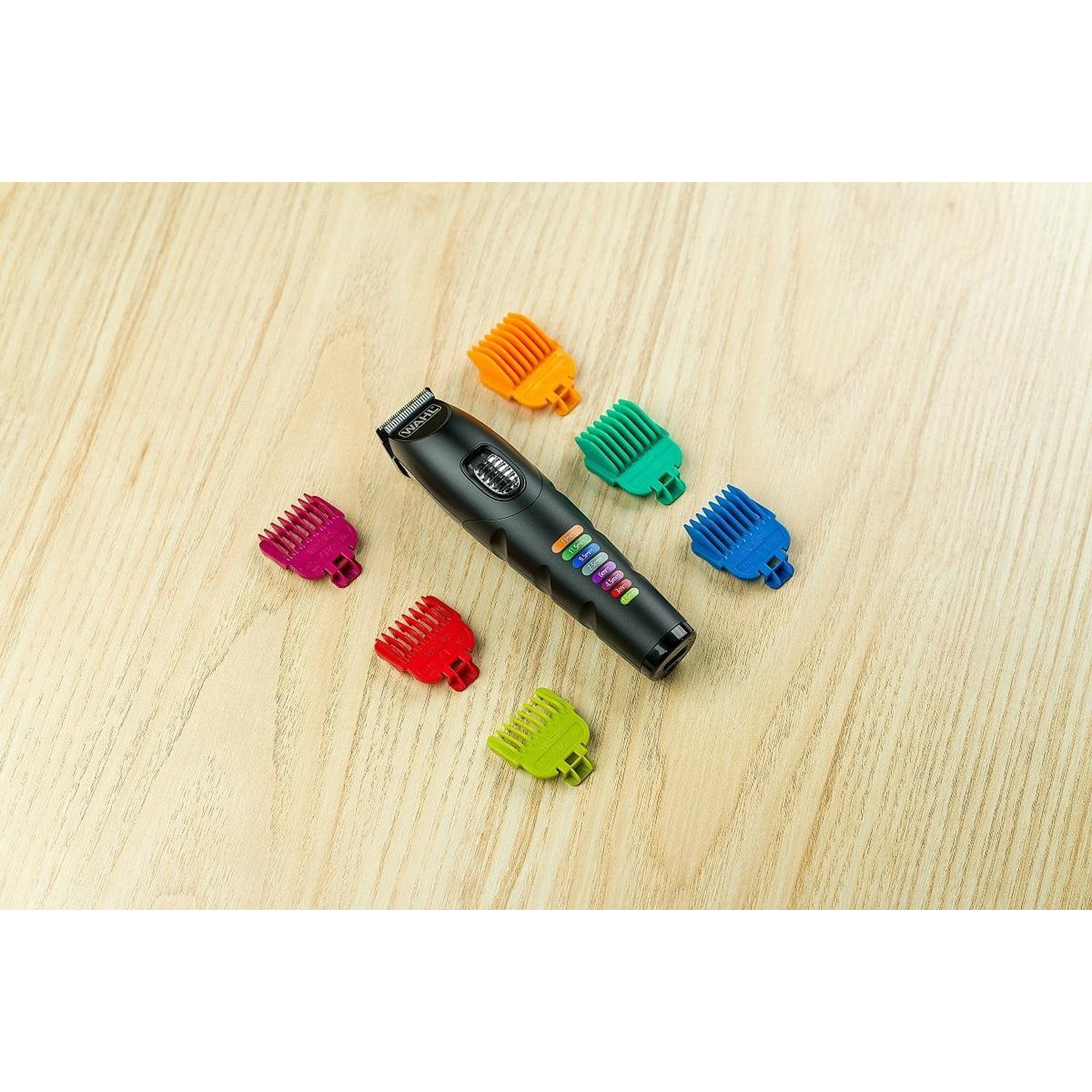 Black hair clipper with colored guards on a wooden surface. Guards are orange, green, blue, red, pink, and yellow.