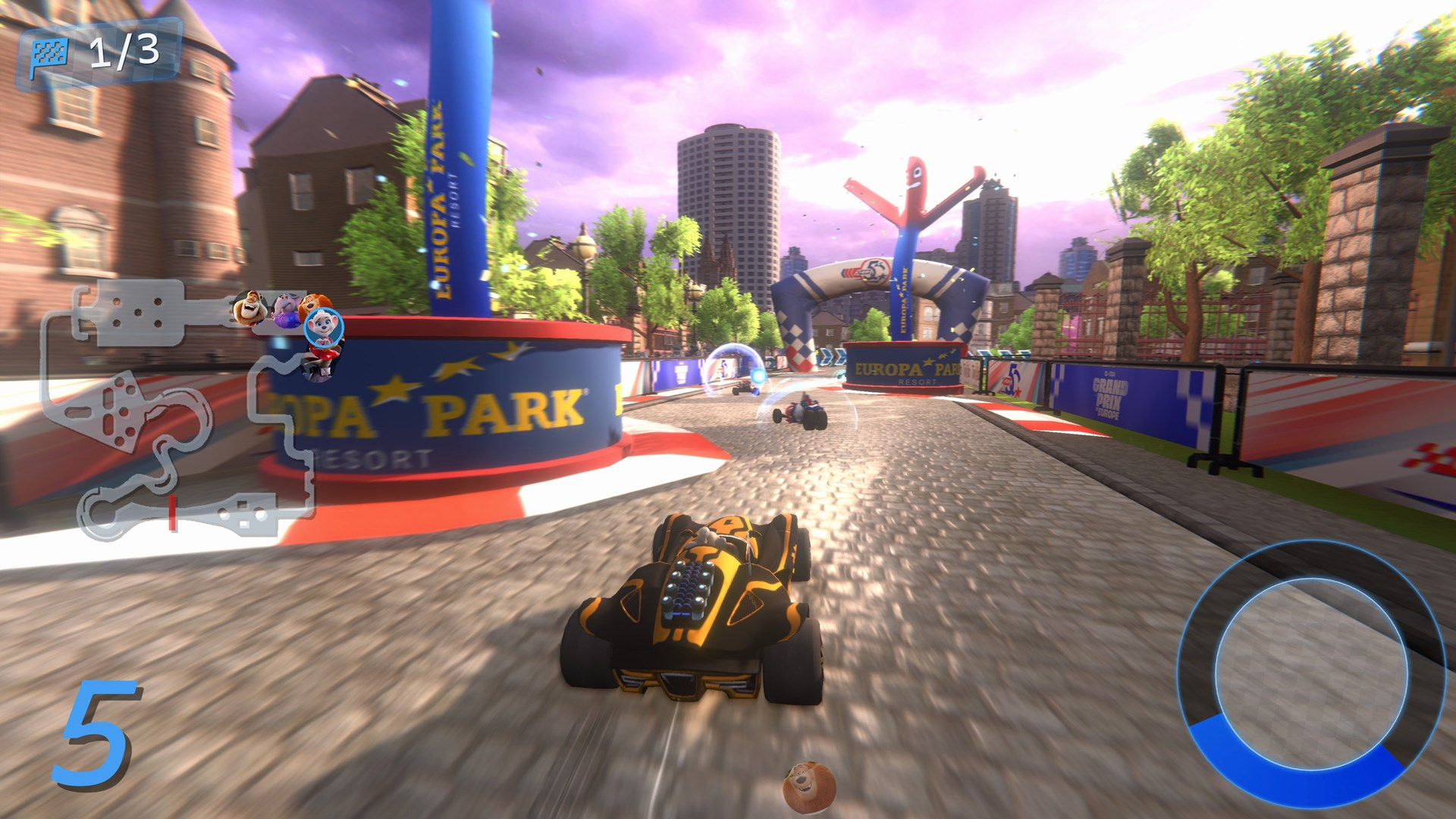 Ein Kart-Rennspiel. Ein schwarz-gelbes Kart fährt auf einer Strecke. Gebäude und eine winkende aufblasbare Figur sind im Hintergrund.