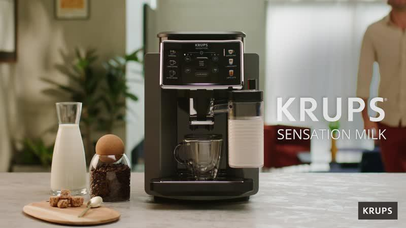 Ekspres do kawy z mlekiem i ziarnami kawy. Osoba w tle. Marka to Krups.