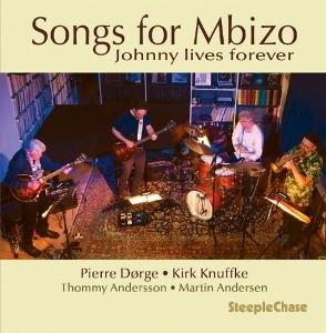 Band spielt auf der Bühne. Vier Musiker mit Instrumenten. Titel: Songs for Mbizo, Johnny lives forever.