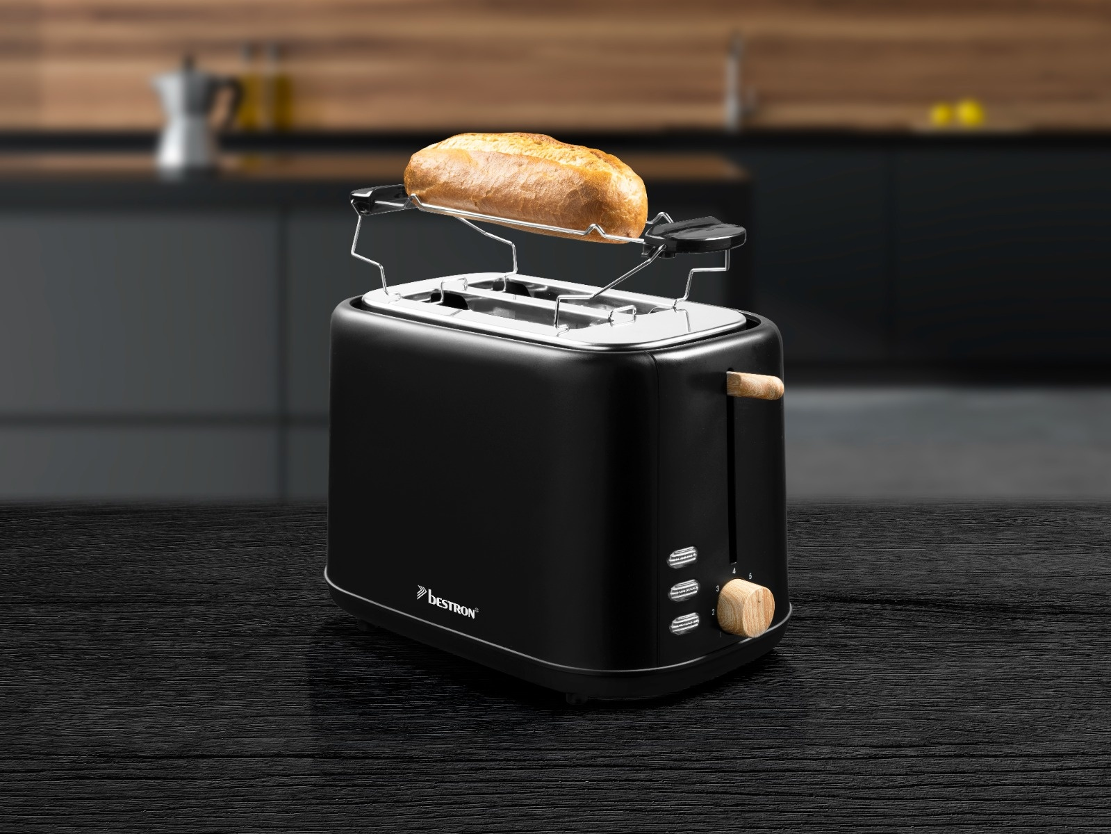 Ein schwarzer Toaster mit einem Brotstück oben drauf. Er hat einen Holzgriff und einen Bedienknopf und steht auf einem schwarzen Holztisch.