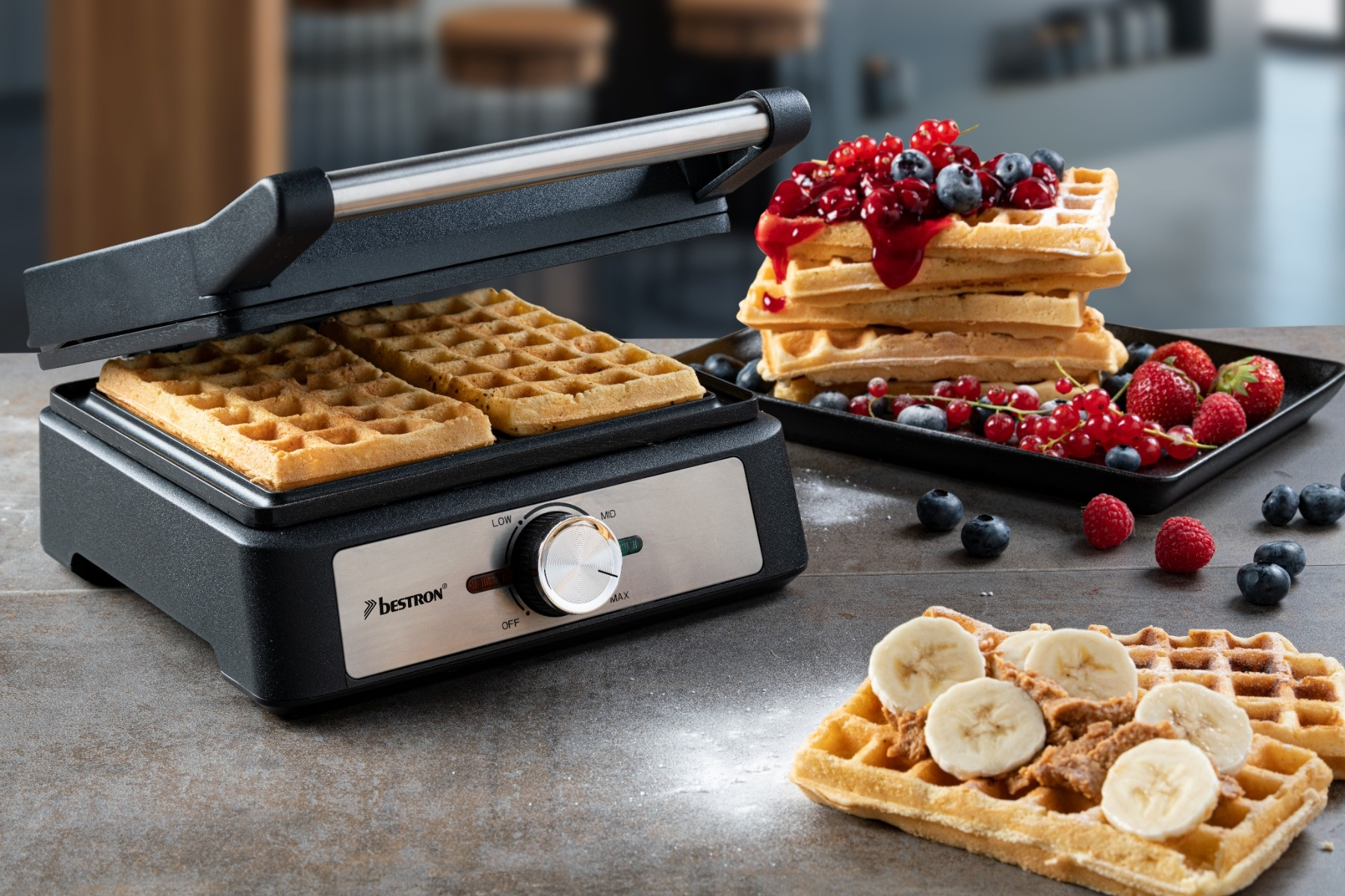 Waffeleisen mit Waffeln, belegte Waffeln mit Beeren und Banane, Himbeeren, Blaubeeren und Johannisbeeren. Dunkler Hintergrund.