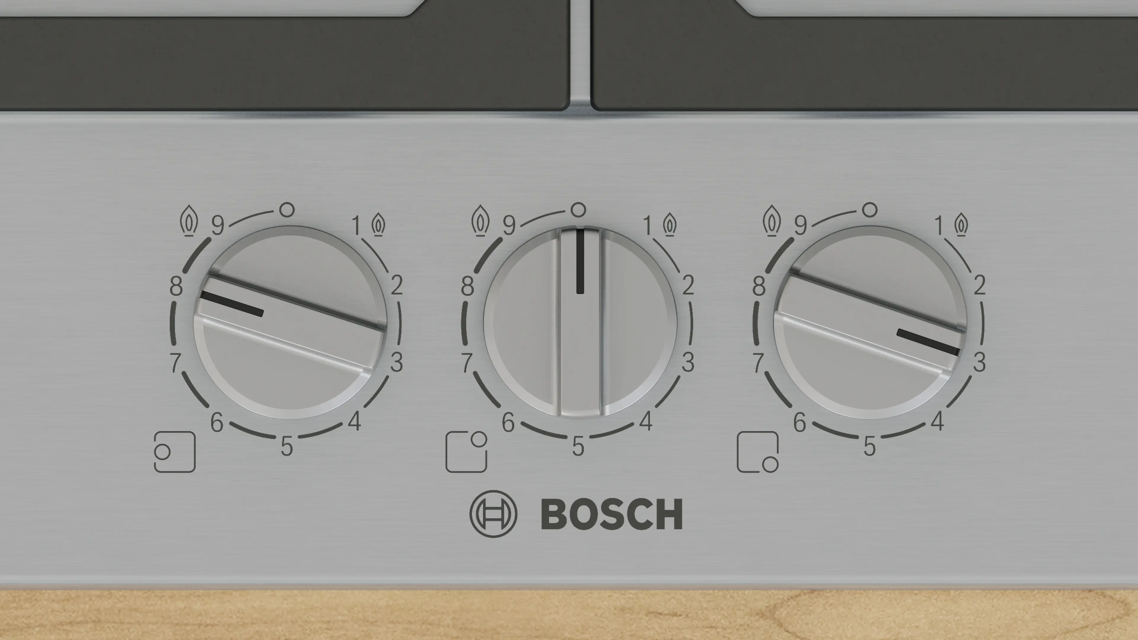 Primer plano de un panel de control de cocina Bosch plateado con tres diales. Cada dial tiene números, un símbolo de llama y un indicador negro.