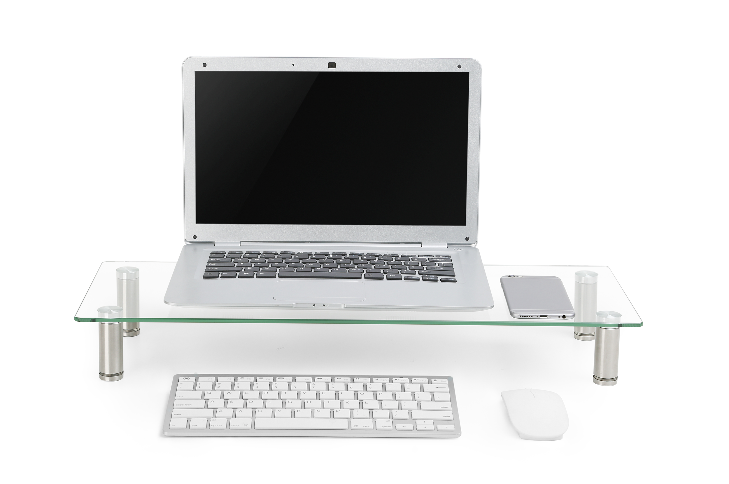 Laptop üvegállványon, billentyűzettel, egérrel és telefonnal fehér felületen. Ezüst és fehér színek.