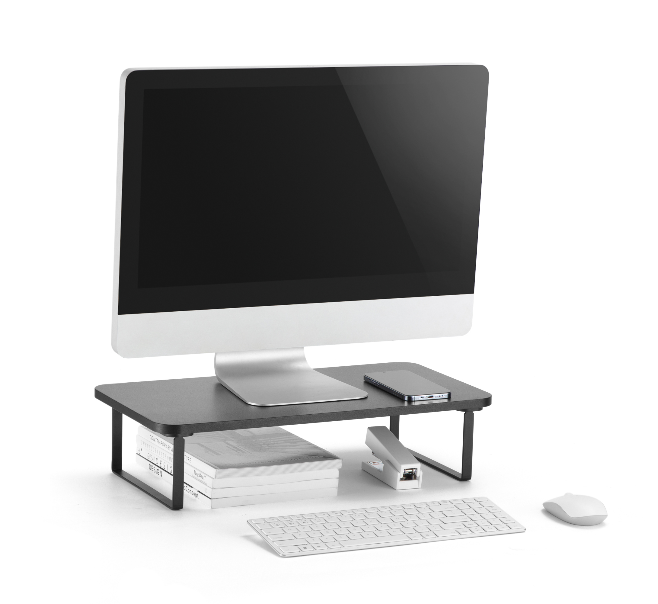 Egy számítógép-beállítás. A monitor egy fekete állványon van, telefonnal, könyvekkel, tűzőgéppel, billentyűzettel és egérrel.