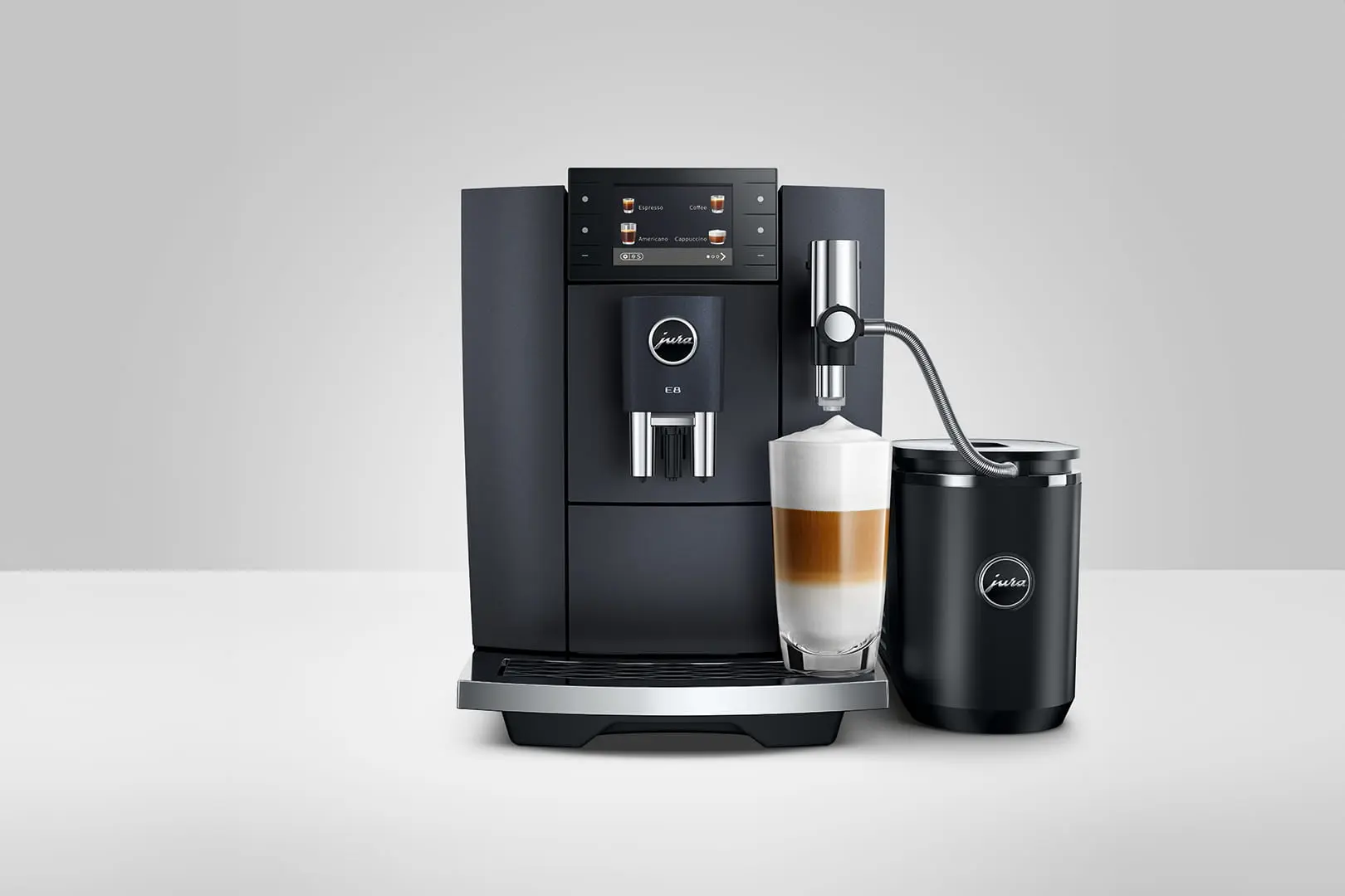 Una macchina da caffè Jura E8 nera con un bicchiere di caffè a strati. Un montalatte è a destra.