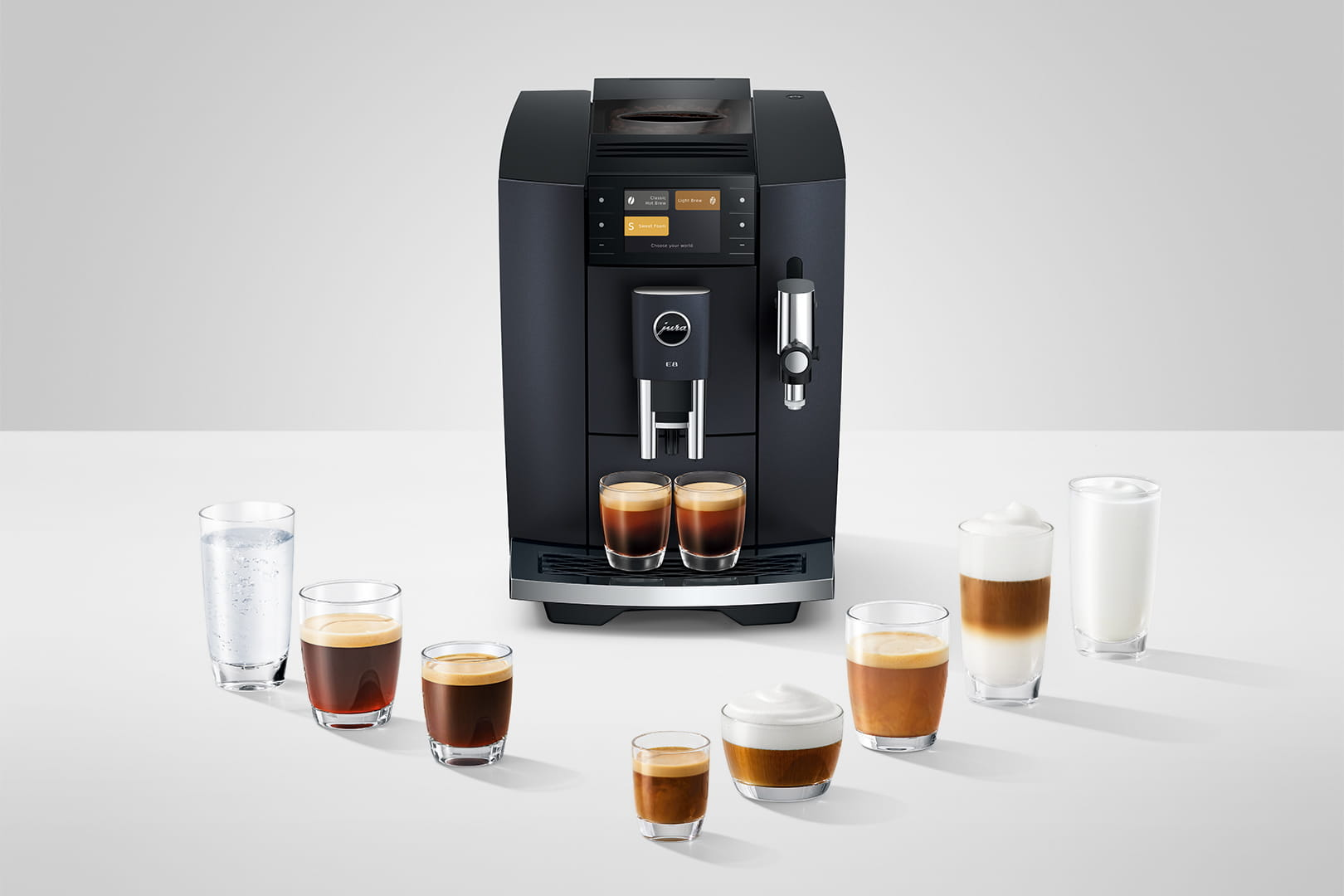 Una macchina da caffè nera con varie bevande al caffè in bicchieri. Uno sfondo bianco.
