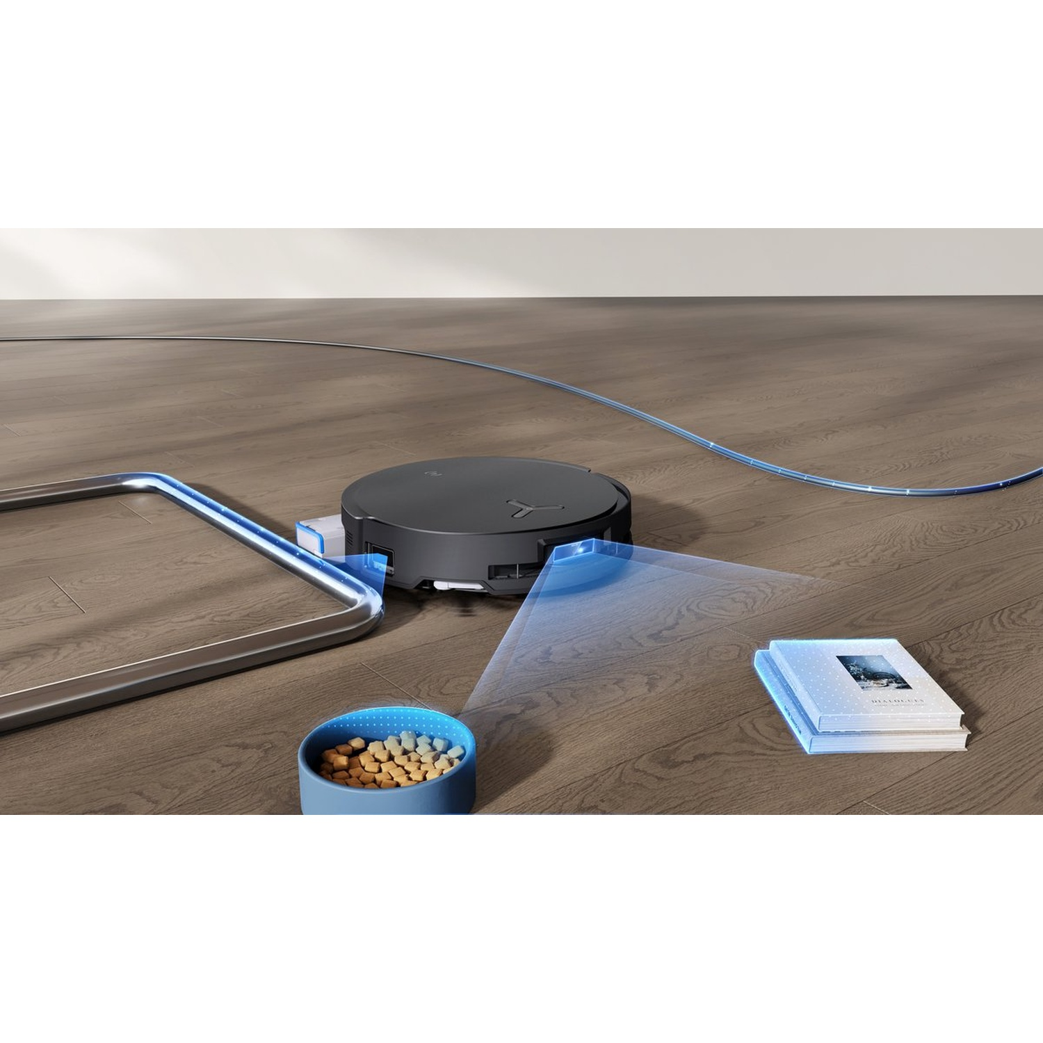 Un aspirateur robot sur un plancher en bois. Un bol pour animaux avec de la nourriture, un livre et une barrière métallique sont à proximité.