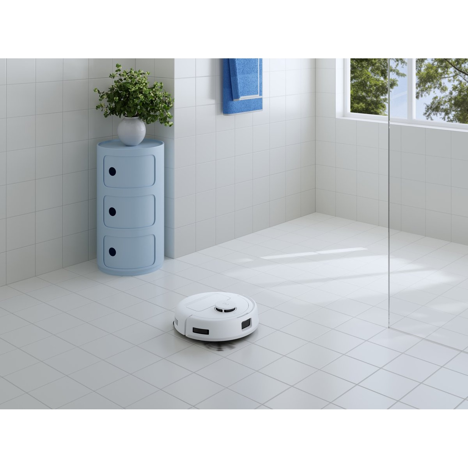 Un aspirateur robot blanc sur un sol carrelé. Une armoire bleue avec une plante, une serviette bleue et une fenêtre en arrière-plan.