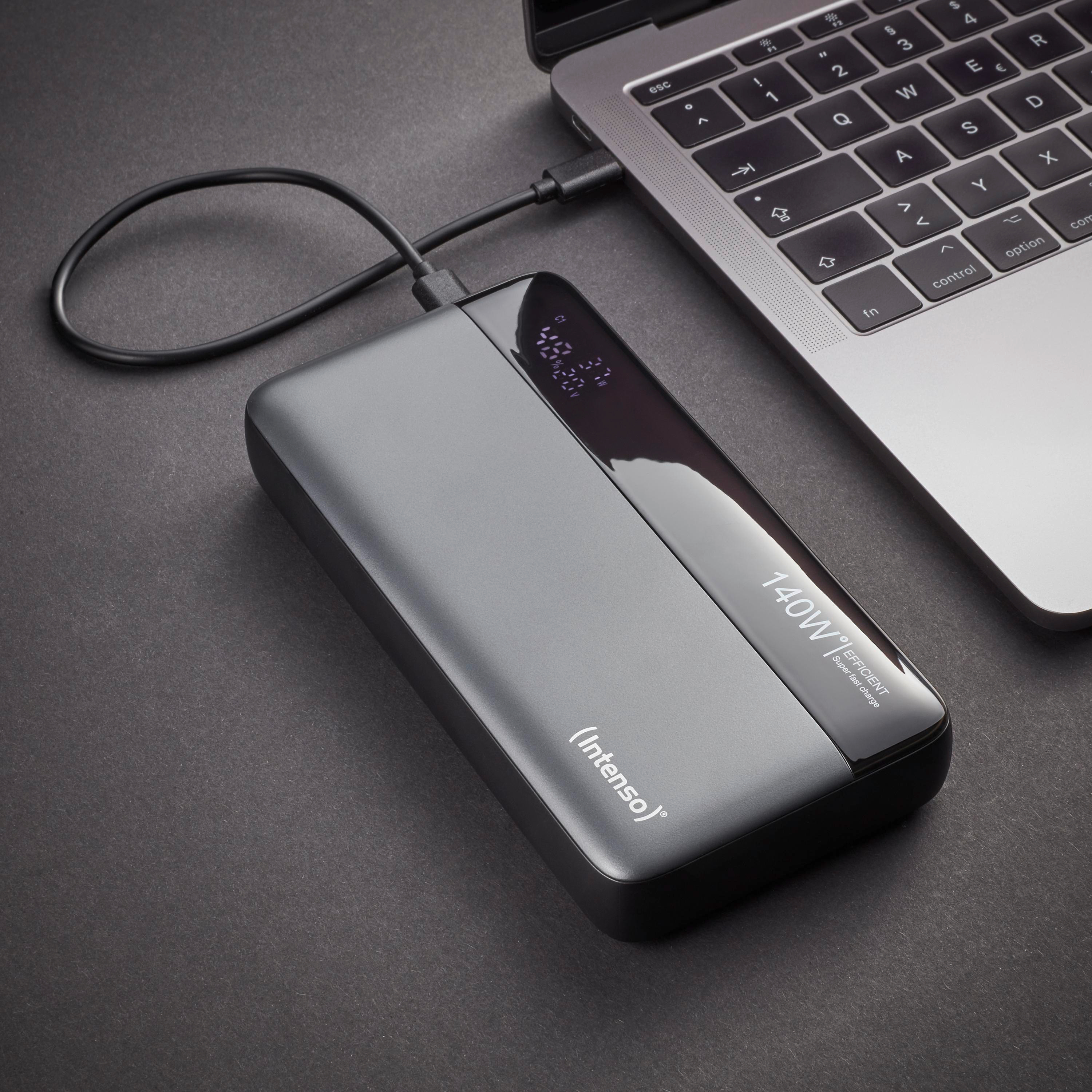 Ein Laptop mit Ladegerät, das an eine graue Powerbank angeschlossen ist. Die Powerbank hat ein Display mit Akkustatistiken.