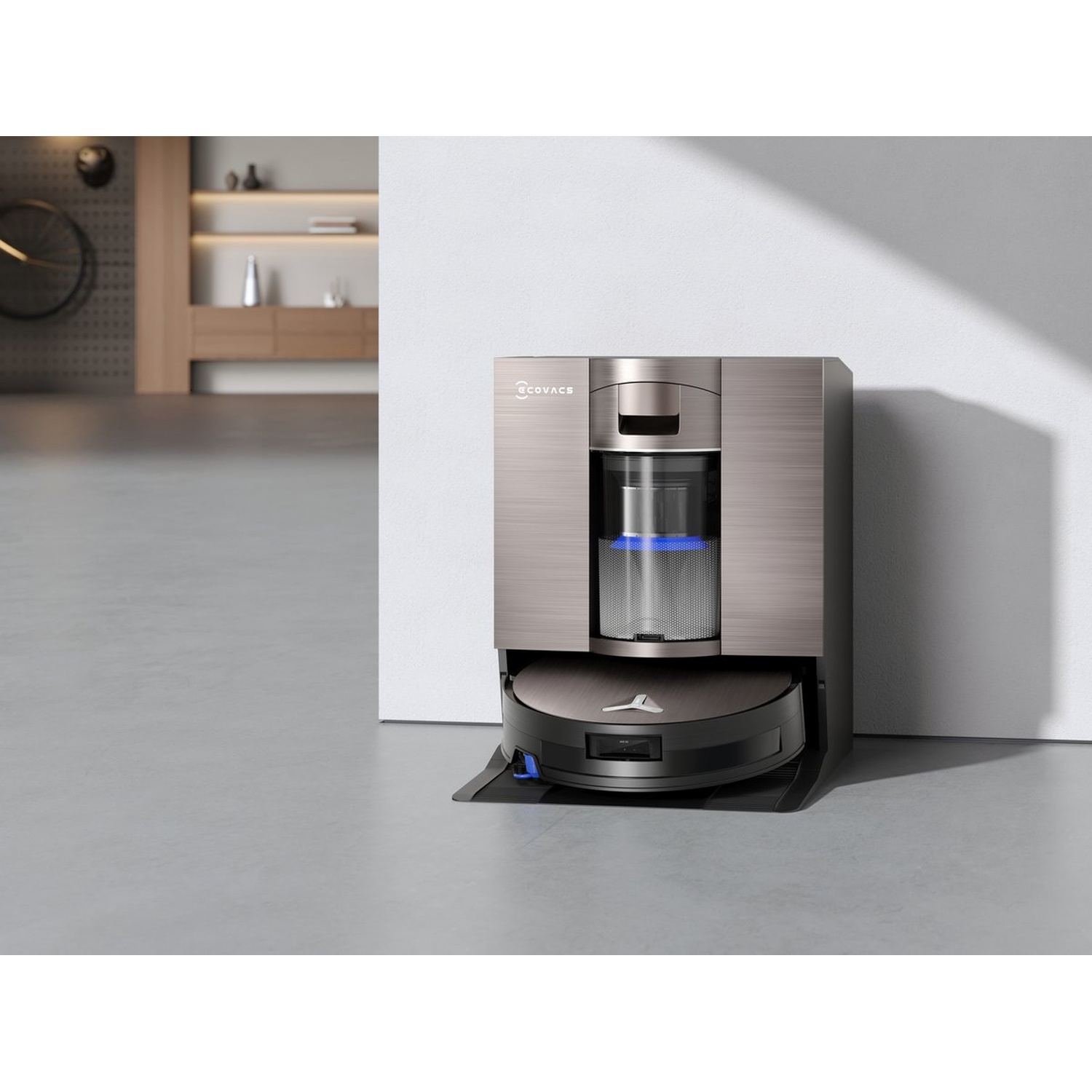 Un aspirateur robot et une station de charge. La station est métallique et le robot est noir. L'arrière-plan montre un intérieur moderne.