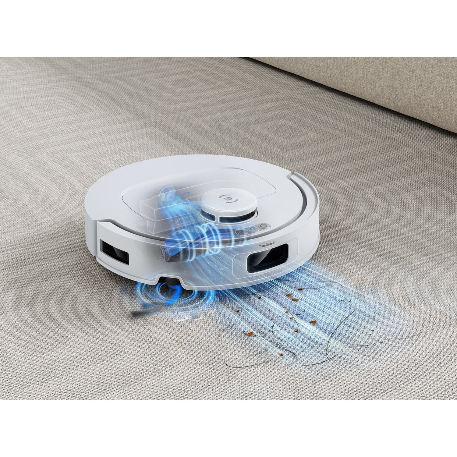 Een witte robotstofzuiger op een tapijt, aan het schoonmaken. Stof en haar worden opgezogen. Een bank staat op de achtergrond.