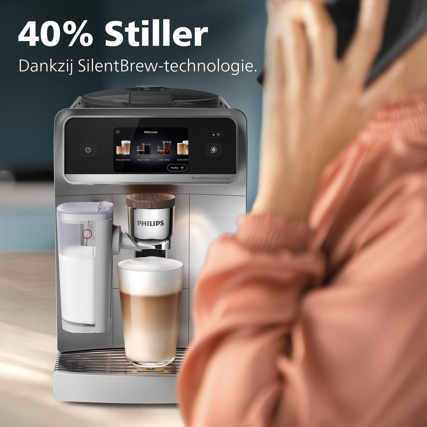 A coffee machine brewing a latte. A person is holding a phone. Text says '40% Stiller' and 'Dankzij SilentBrew-technologie.'