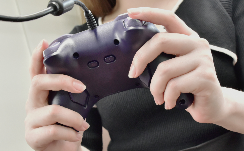 Eine Person hält einen lila Gamecontroller. Hände sind um den Controller. Ein schwarzes Kabel ist mit dem Controller verbunden.