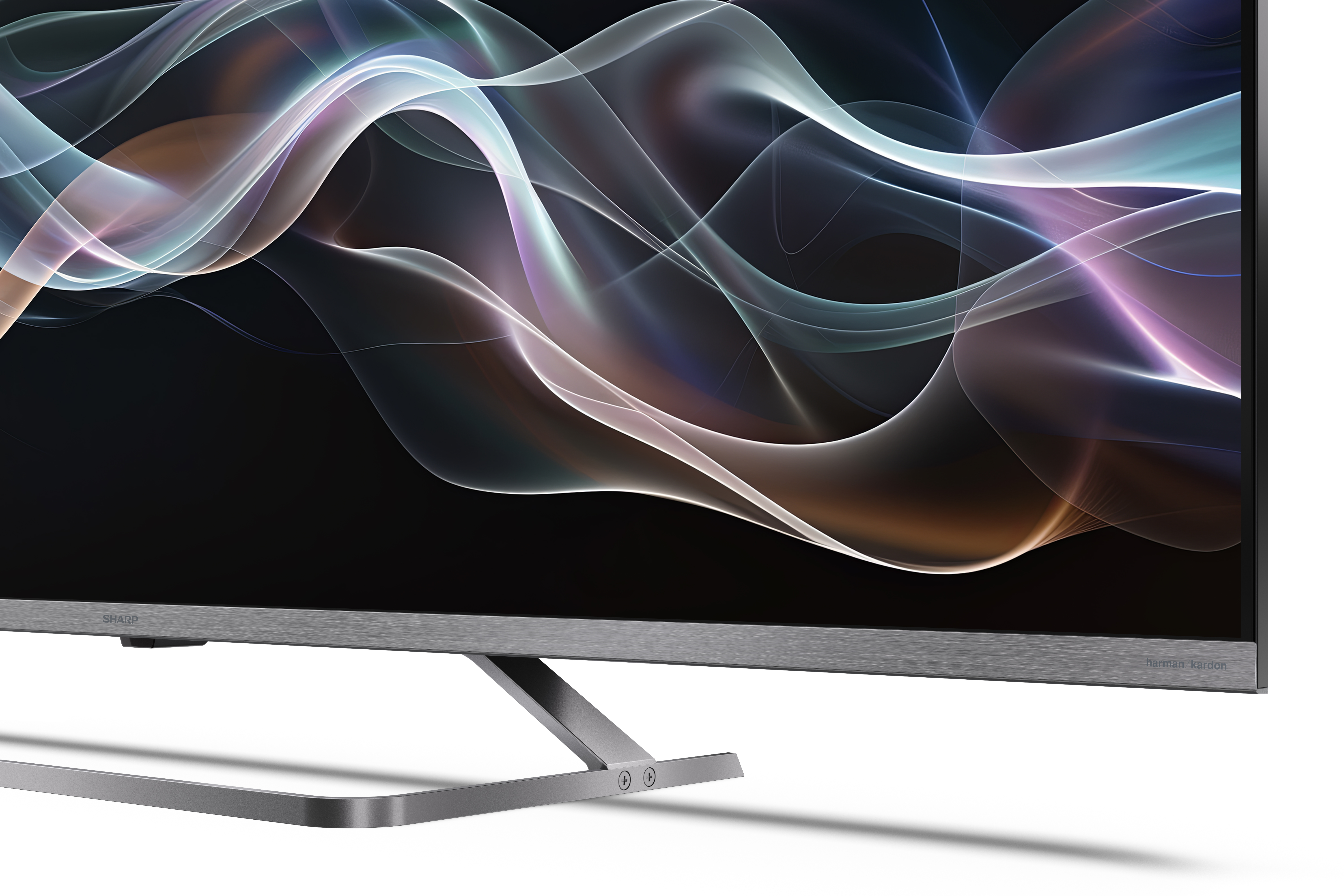 A Sharp TV színes, absztrakt hullámokat jelenít meg. A TV ezüstszínű, fekete kerettel és fémállvánnyal.