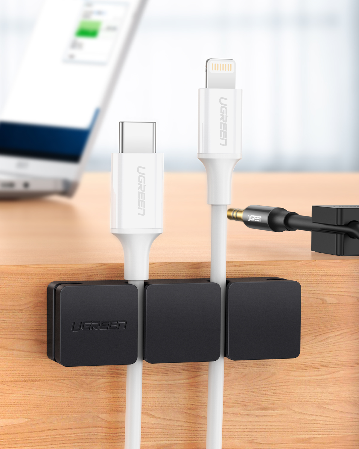 Siyah tutucularda beyaz USB-C ve Lightning kabloları. Siyah bir ses adaptörü ve bulanık bir tablet de mevcut.