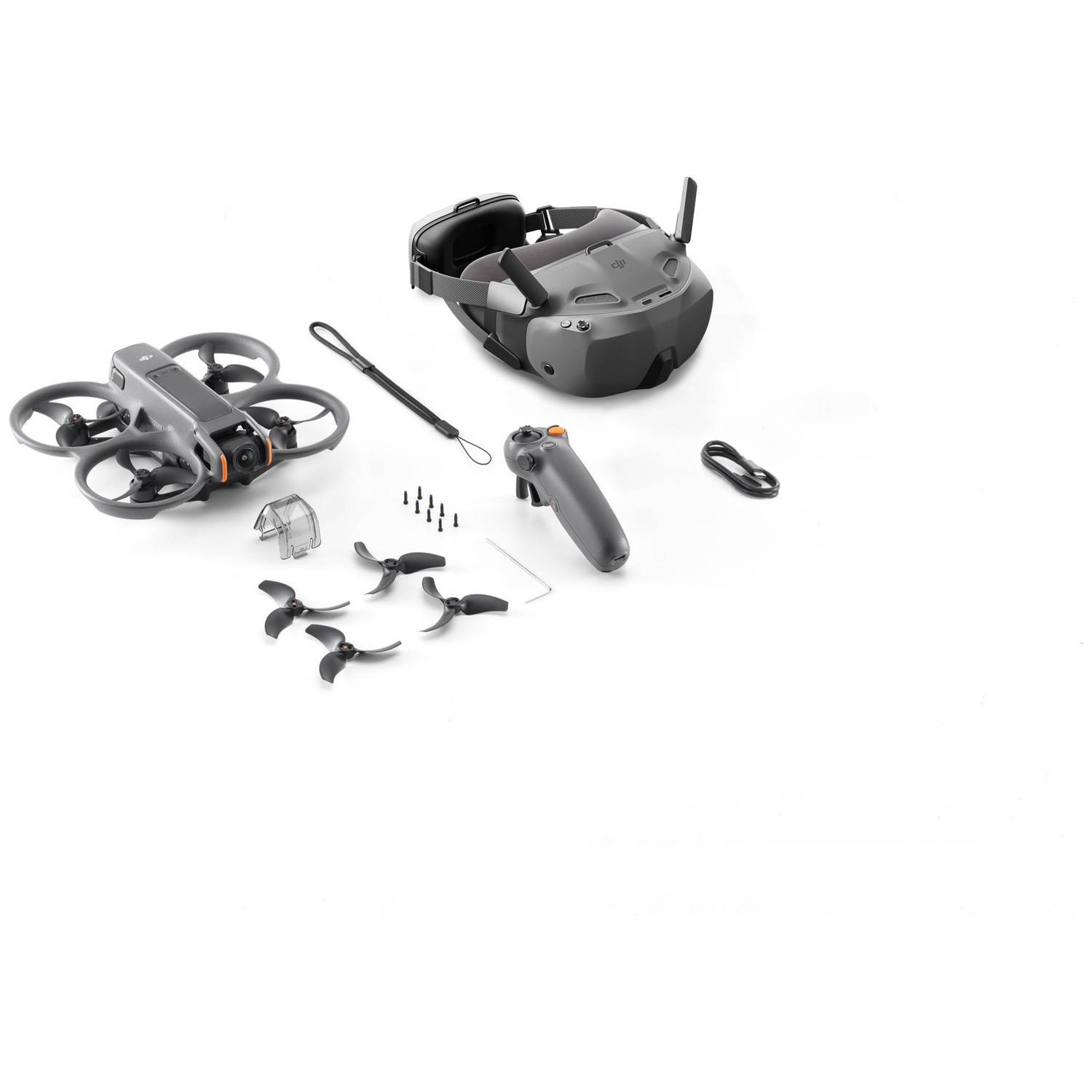 Drone, lunettes, télécommande et accessoires sur une surface blanche. Le drone est gris, avec des hélices noires. Les lunettes sont également grises.