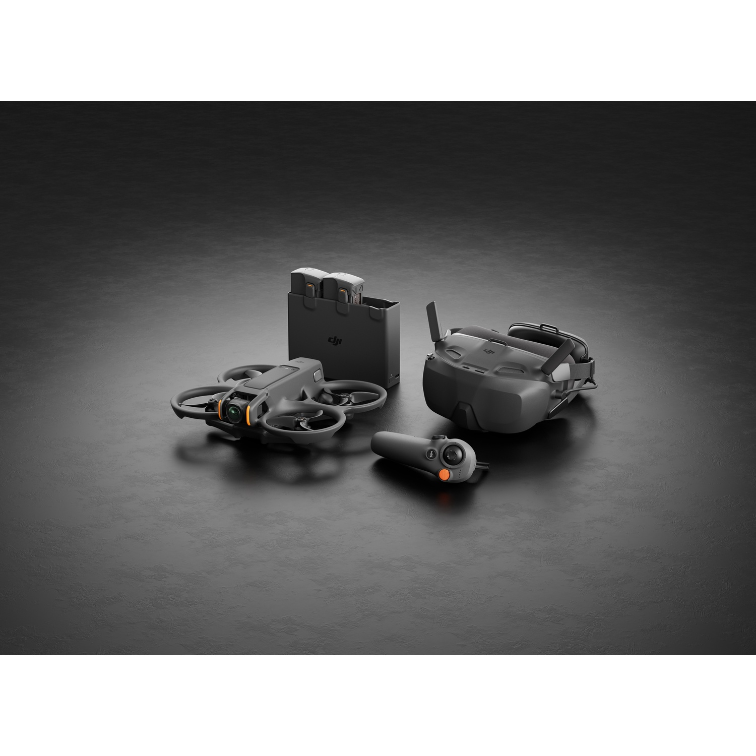 Een dronekit op een zwart oppervlak. Het bevat een drone, een bril, een afstandsbediening en een oplader met twee batterijen.