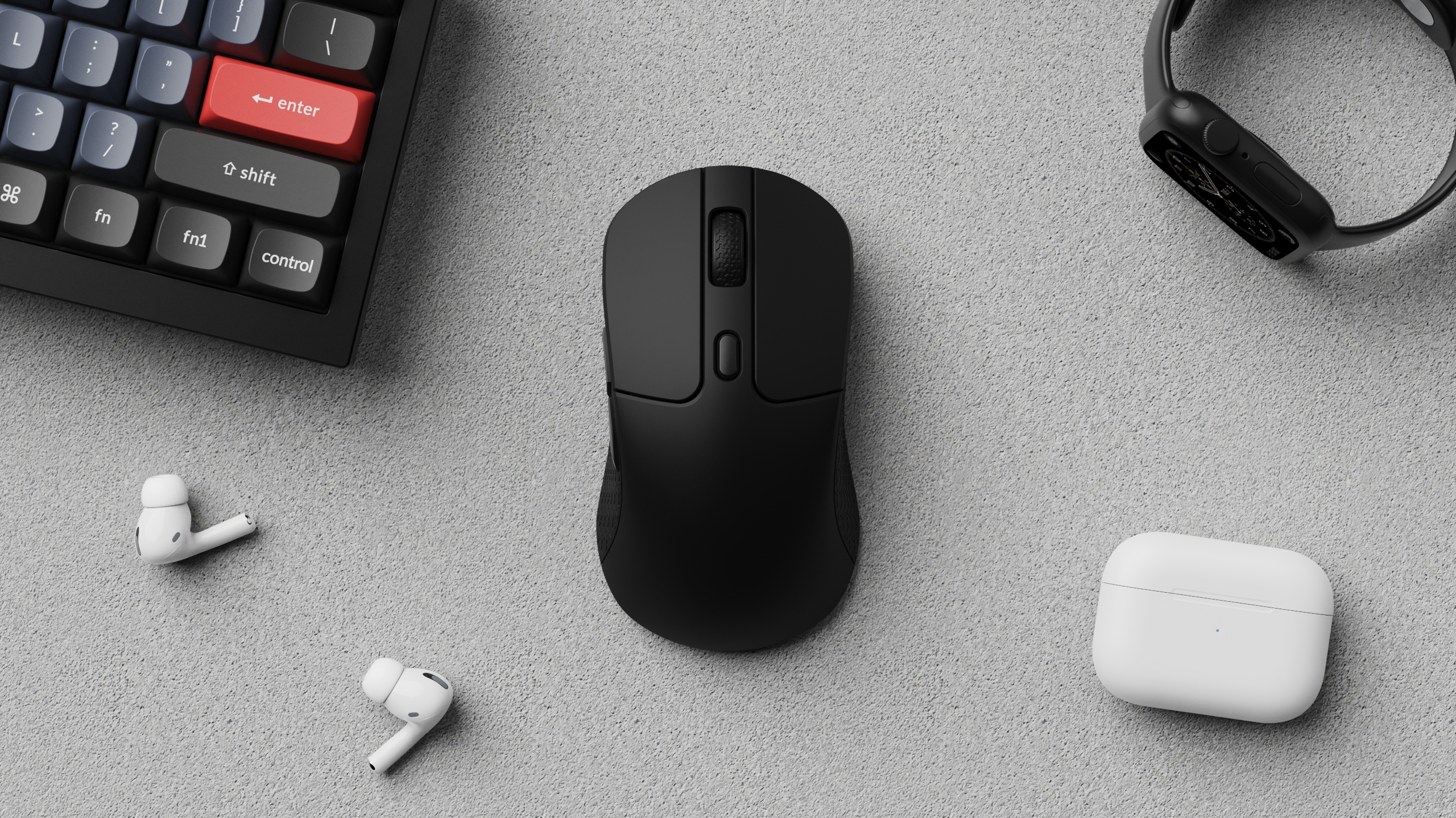 Eine schwarze Tastatur, Maus, Uhr und weiße Ohrhörer und Hülle auf einer grauen Oberfläche. Die Tastatur hat eine rote Eingabetaste.