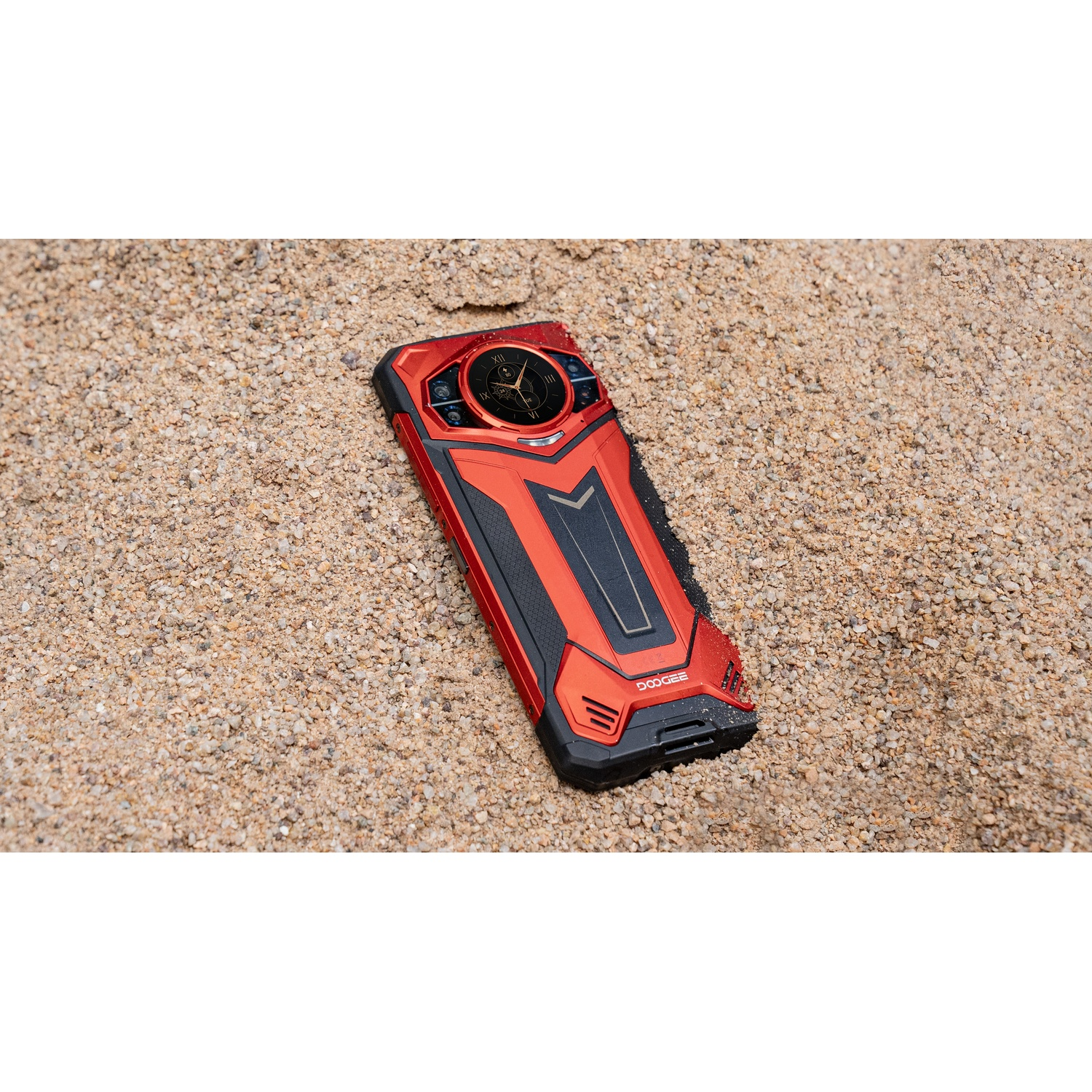 Uno smartphone Doogee rosso e nero è appoggiato sulla sabbia. Il telefono ha un design unico con più fotocamere e un esterno robusto.