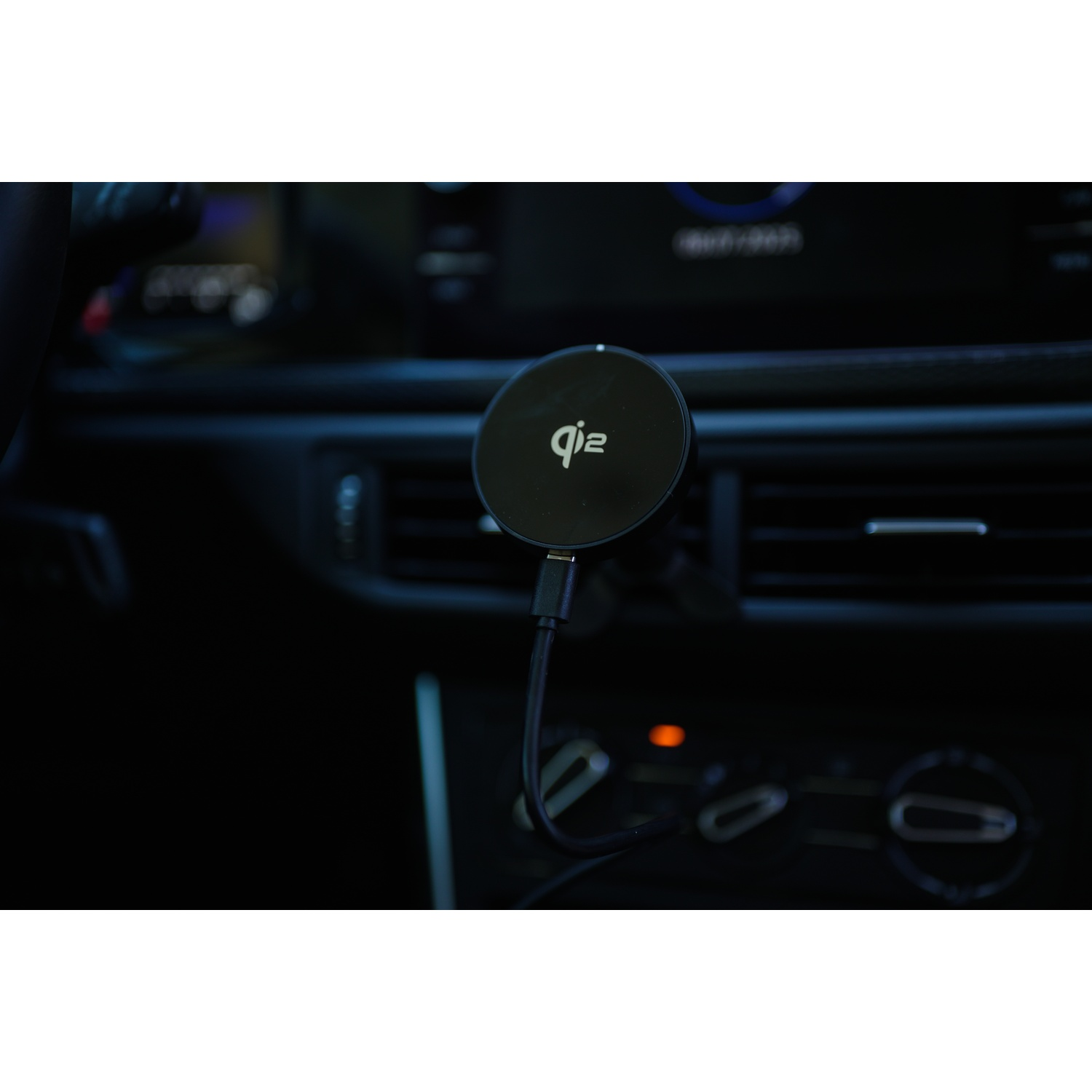 Un caricabatterie wireless Qi2 nero è montato in un'auto. È collegato a un cavo, con un cruscotto scuro sullo sfondo.