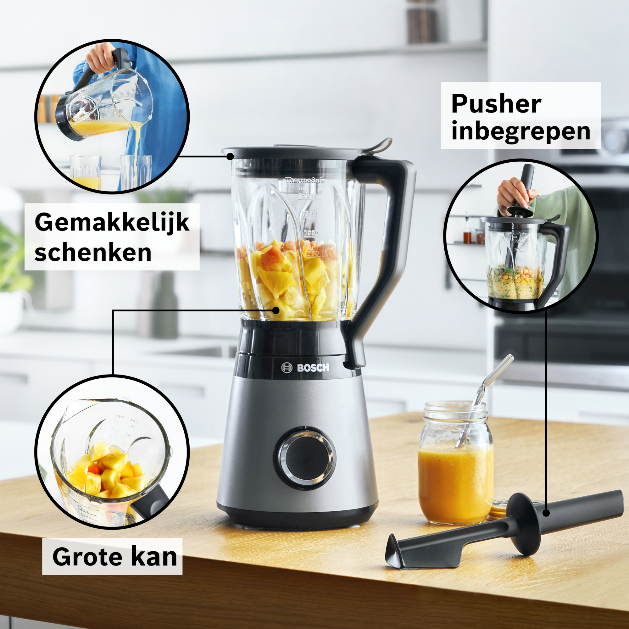 A Bosch blender with fruit inside. It has a large jug, a pusher and a glass with orange juice. The background is blurred.