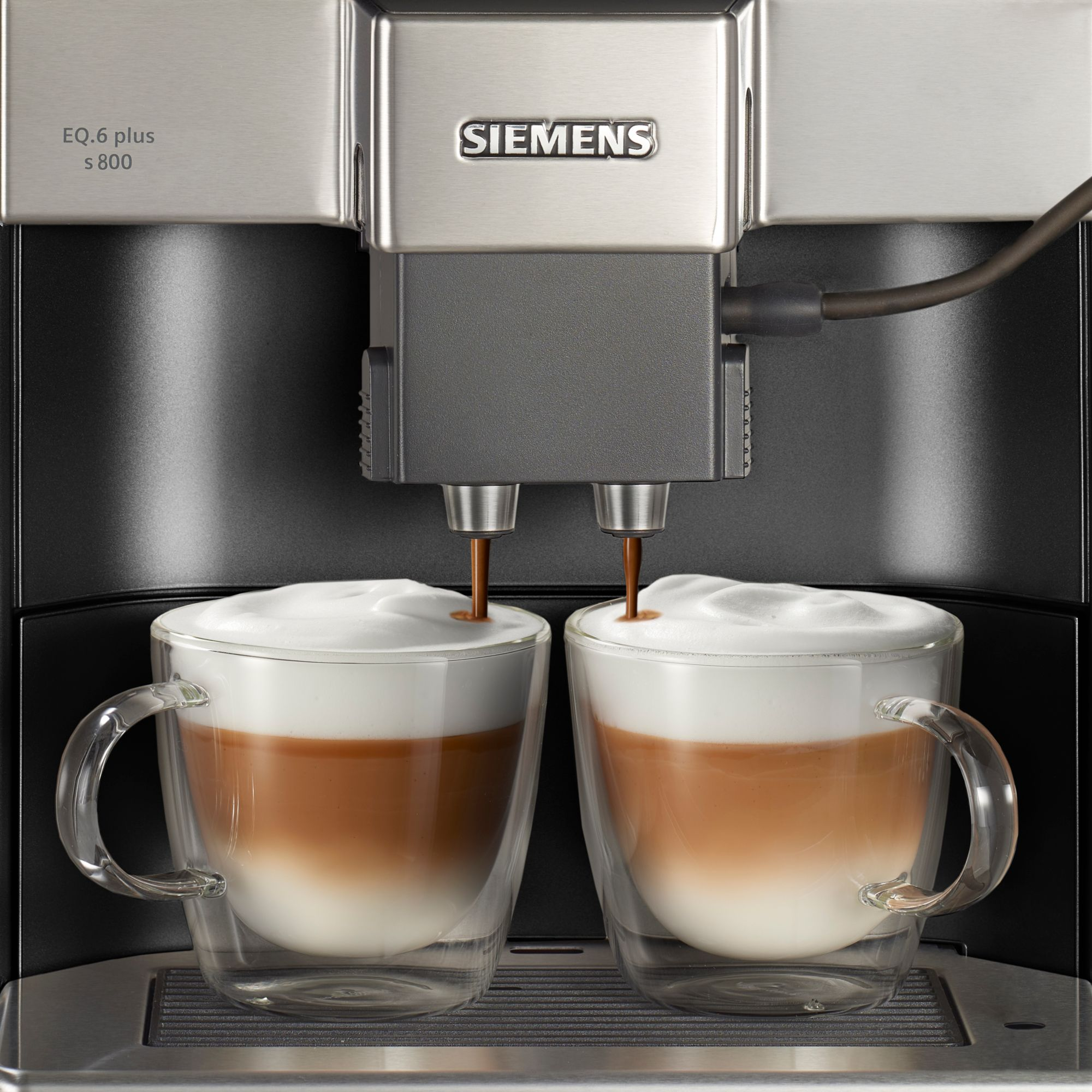 Koffiemachine die koffie schenkt in twee doorzichtige mokken met latte art. De machine heeft het Siemens-logo.
