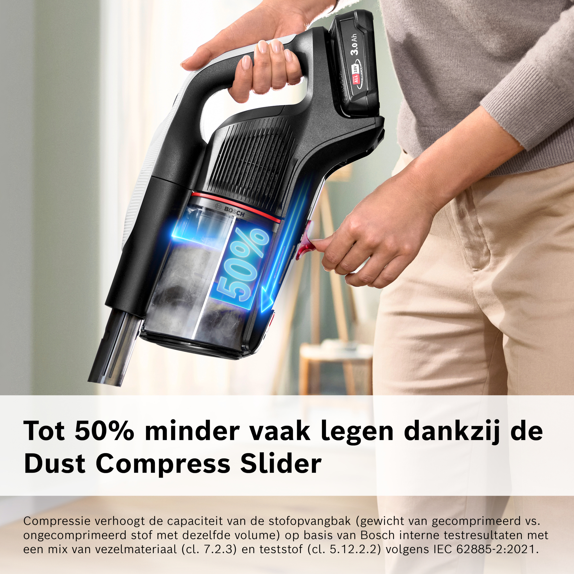 A person holds a black and white vacuum cleaner. The cleaner has a clear dustbin with 50% displayed.