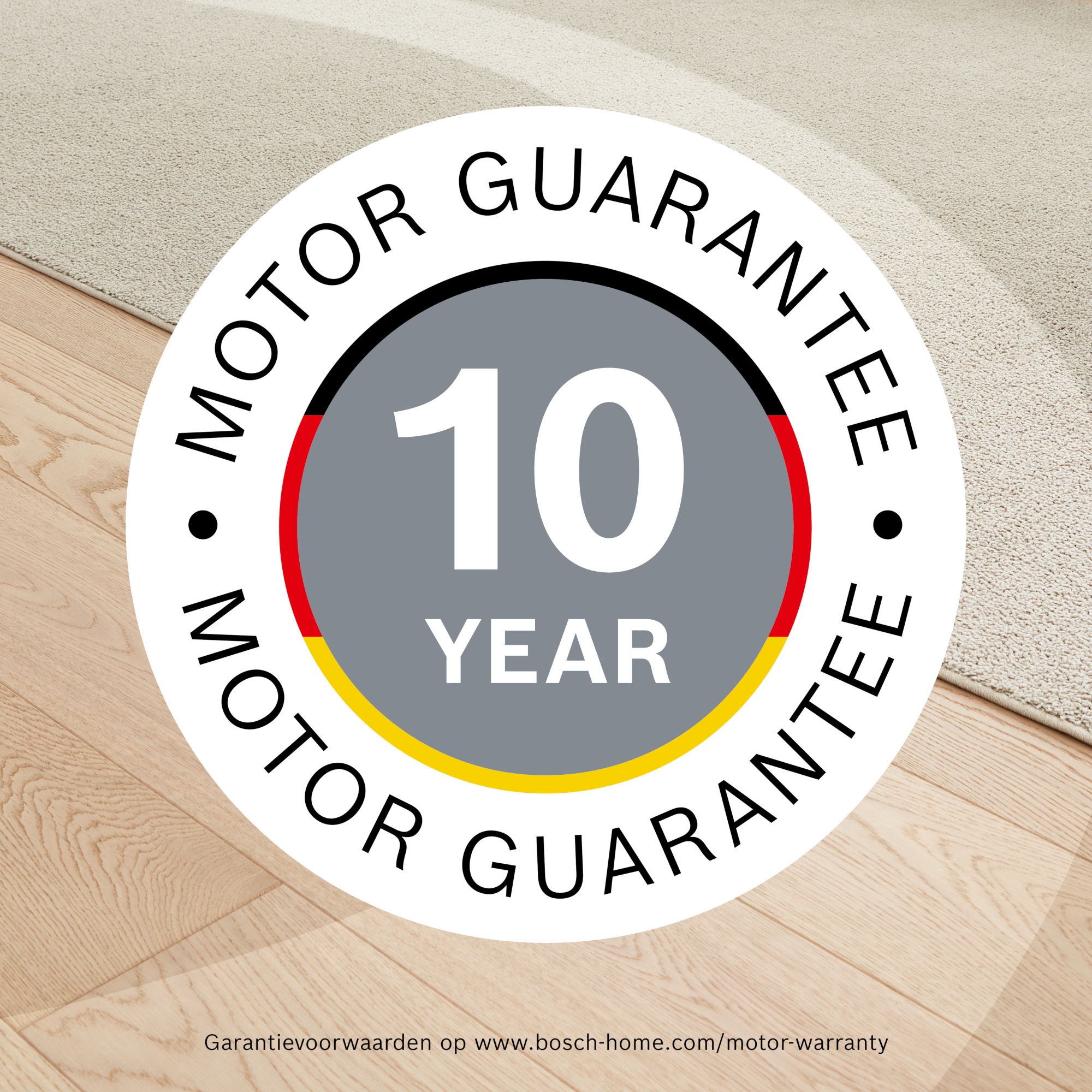 A round logo with 'MOTOR GUARANTEE' text, a German flag, and a '10 YEAR' claim against a wooden floor and beige rug.