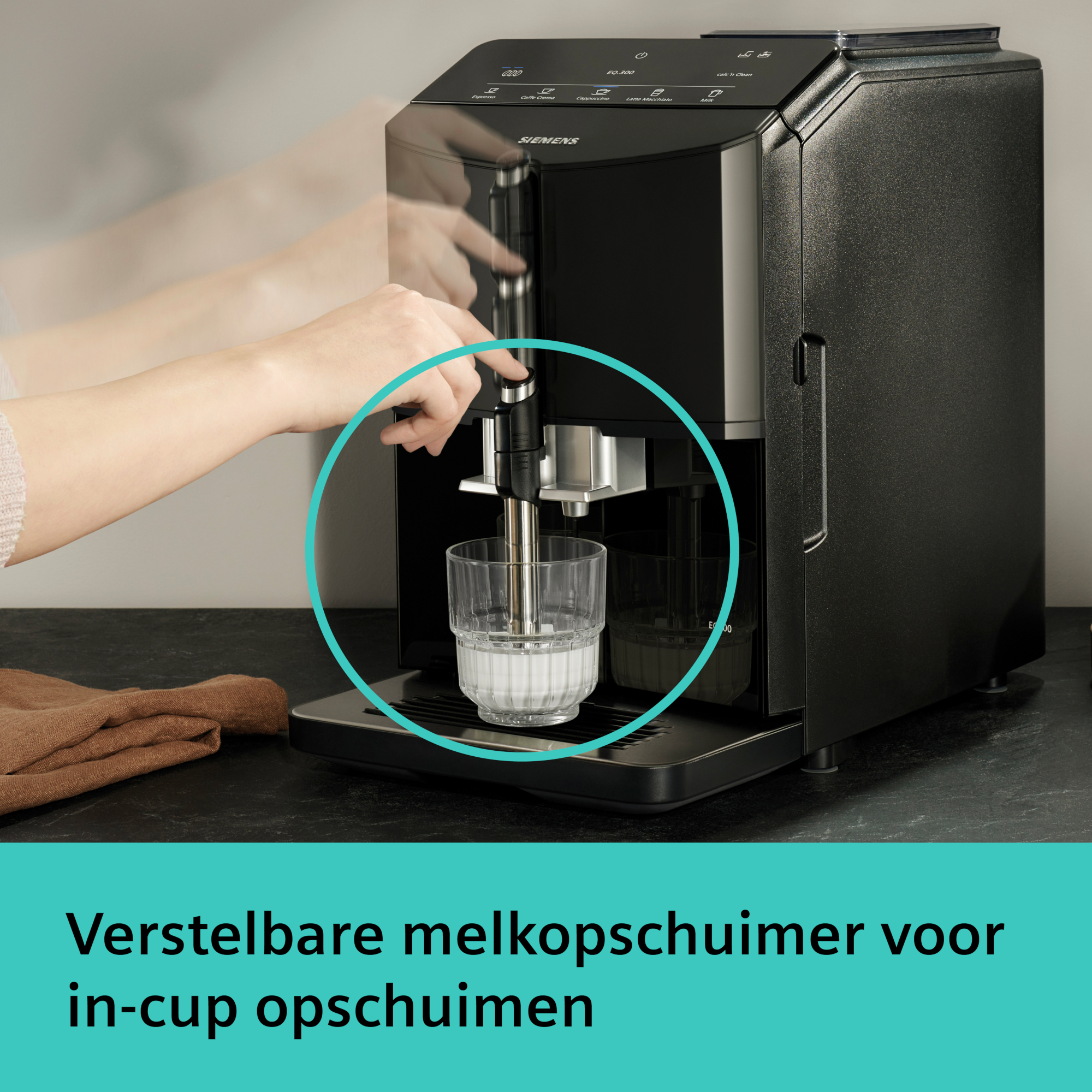 Een zwarte espressomachine met een hand die melk in een glas giet. Een bruine doek ligt links.