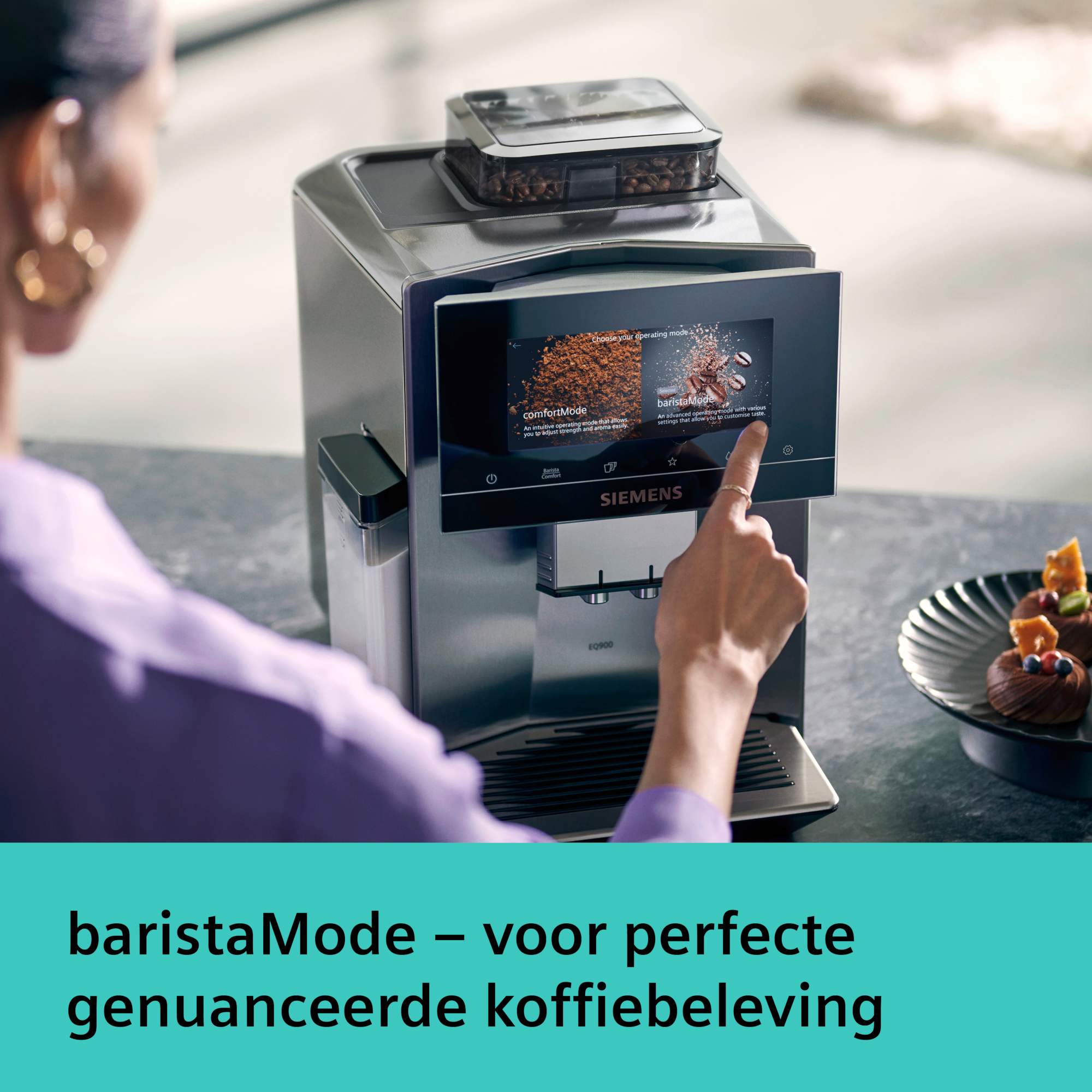 A woman's hand touches a coffee machine screen. It shows baristaMode. A plate with pastries is on the right.