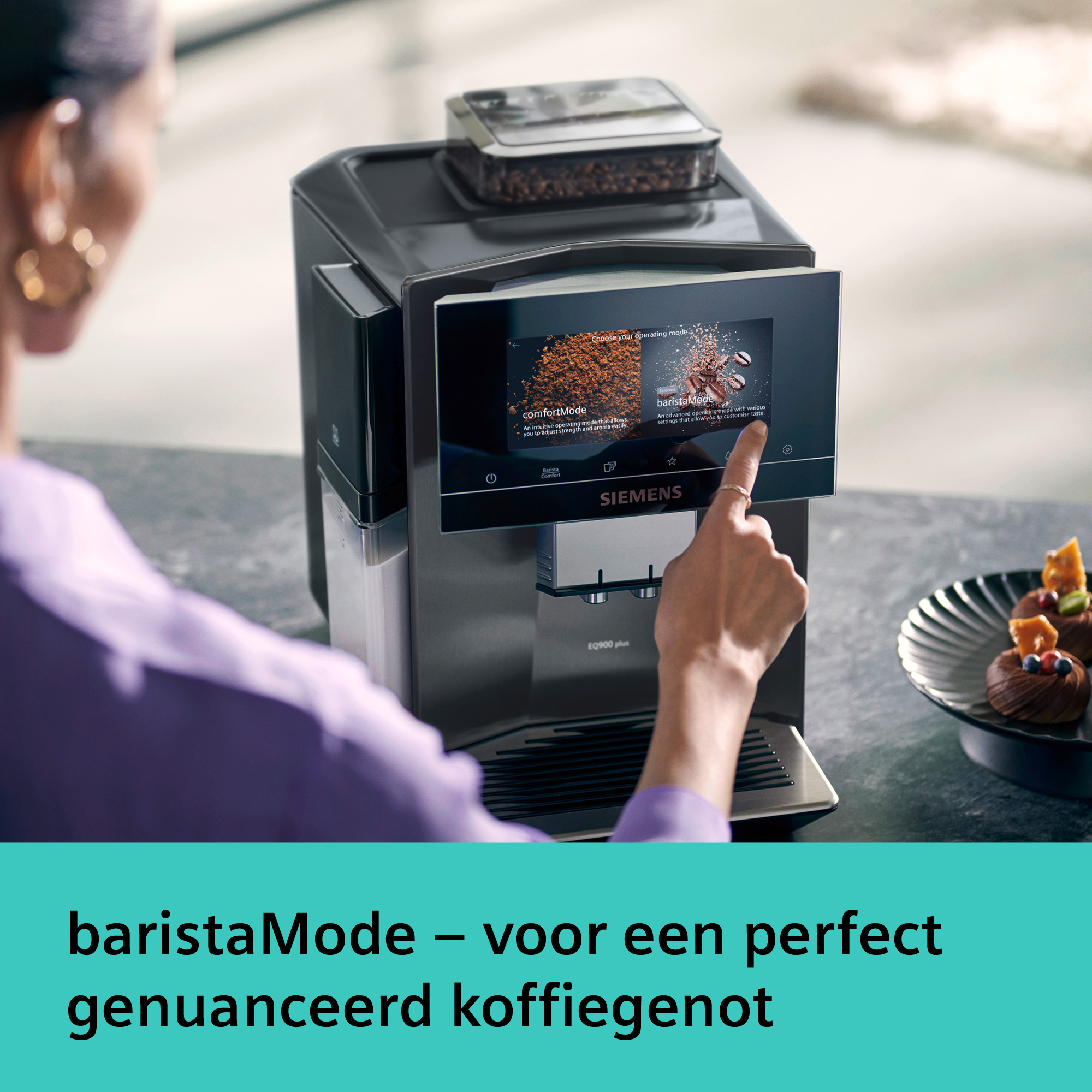 A woman's hand touches a coffee machine screen. The screen shows coffee options. A plate of desserts is nearby.