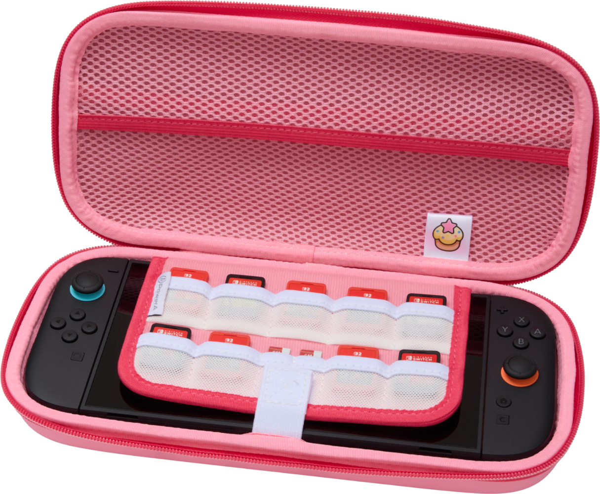 Nyitott rózsaszín Switch hordtáska, Switch konzollal és játékkazettákkal. Egy cupcake logó látható a belsejében.