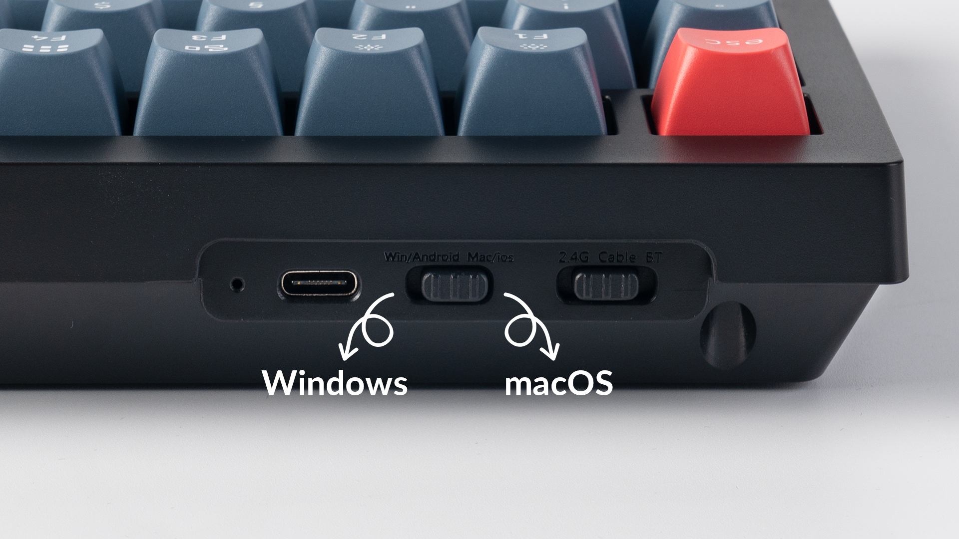 Nahaufnahme einer schwarzen Tastatur. Merkmale USB-C-Anschluss, Schalter für Win/Android/Mac/iOS und 2.4G/Kabel/BT und blaue Tasten.