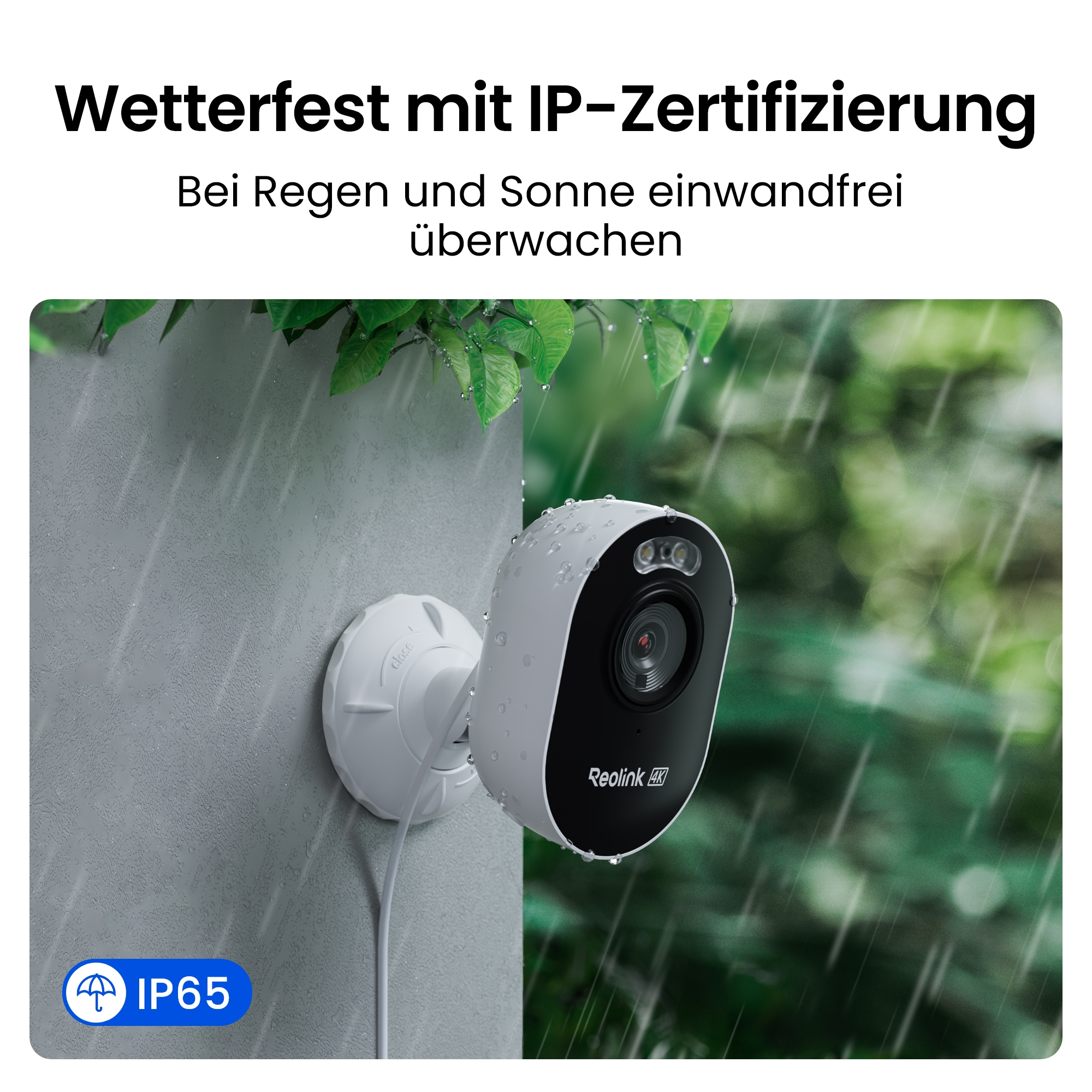 Eine weiße und schwarze Überwachungskamera an einer Wand. Regentropfen sind sichtbar. Grünes Laub im Hintergrund.