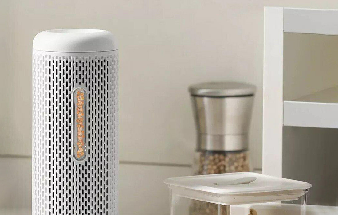 Biały i srebrny osuszacz stoi na blacie z młynkiem do przypraw i przezroczystym pojemnikiem. Tło kuchni.