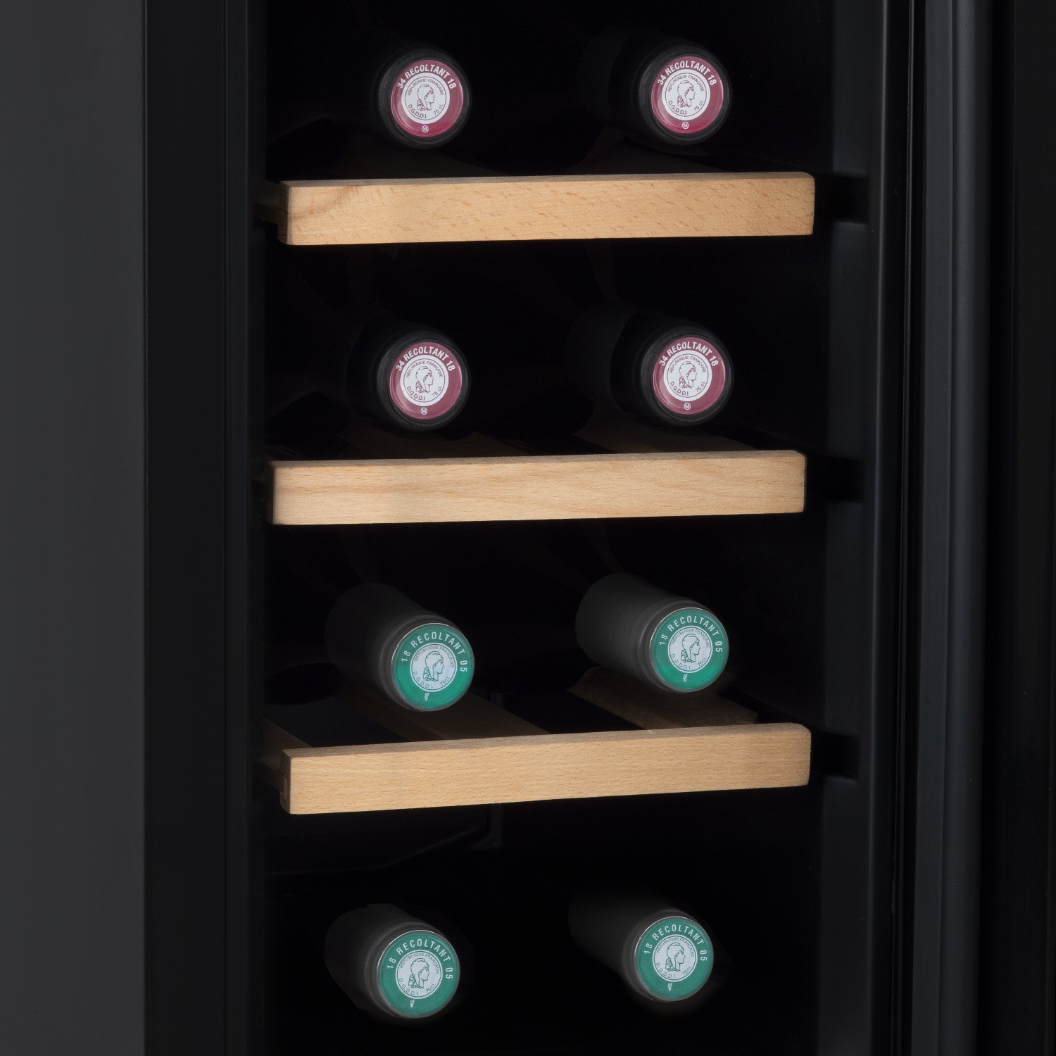 Bottiglie di vino conservate in un frigo per vini. Le bottiglie sono su ripiani di legno. Alcune hanno etichette rosse, altre verdi.