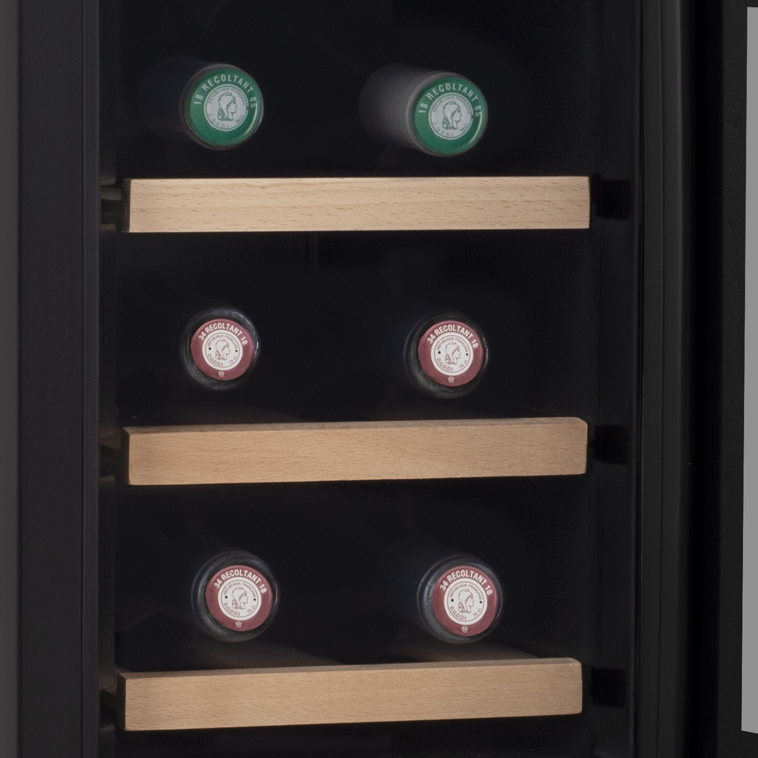 All'interno di un frigorifero per vini, bottiglie con etichette verdi e rosse poggiano su scaffali di legno. Interno nero, porta a vetri.